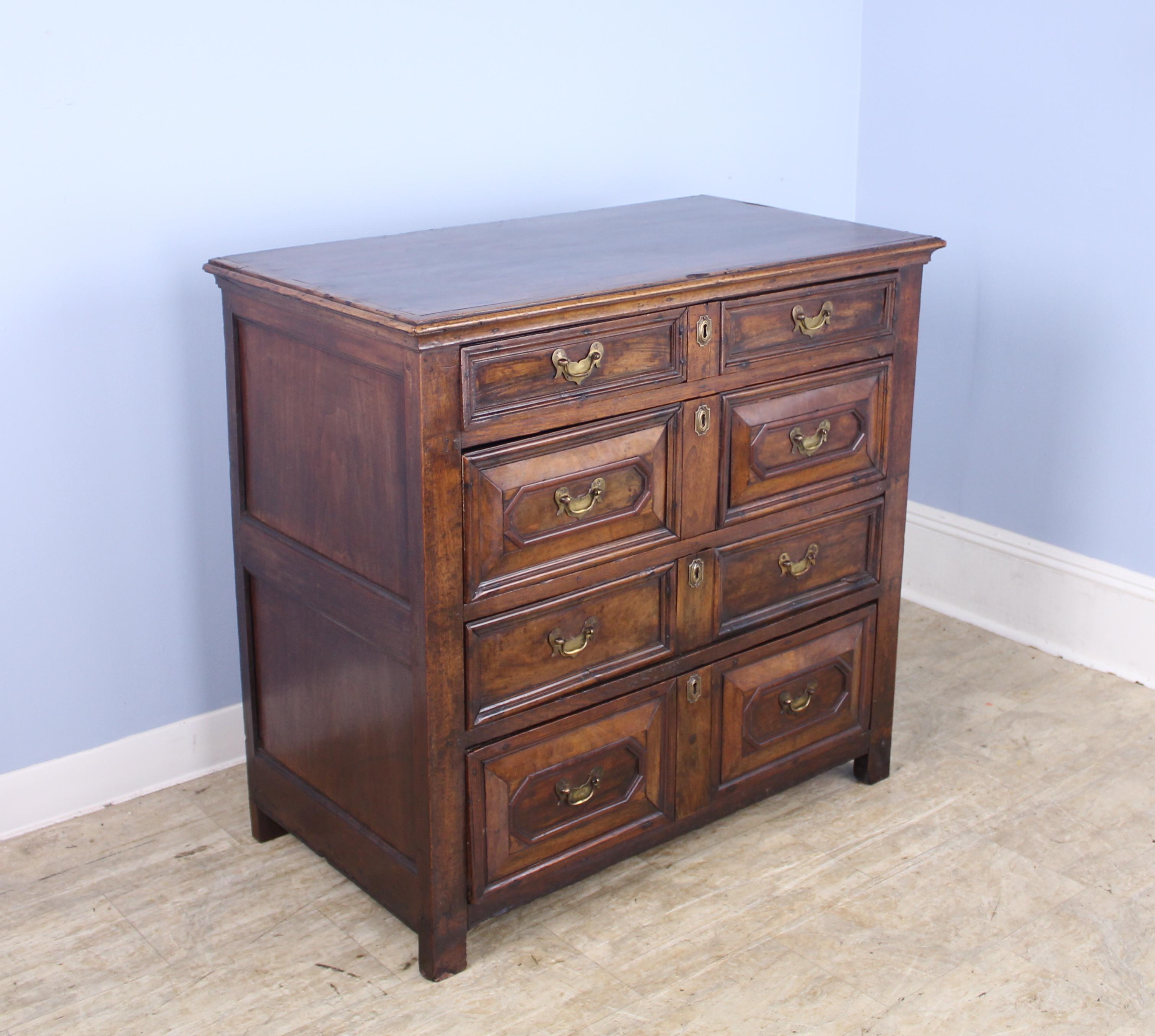 A fine example of a period Jacobean moulded chest of drawers, with inset panels on the side and a raised geometric pattern on the drawers. The color and patina of the walnut are superb. Original brass handles. There is some distress and separation