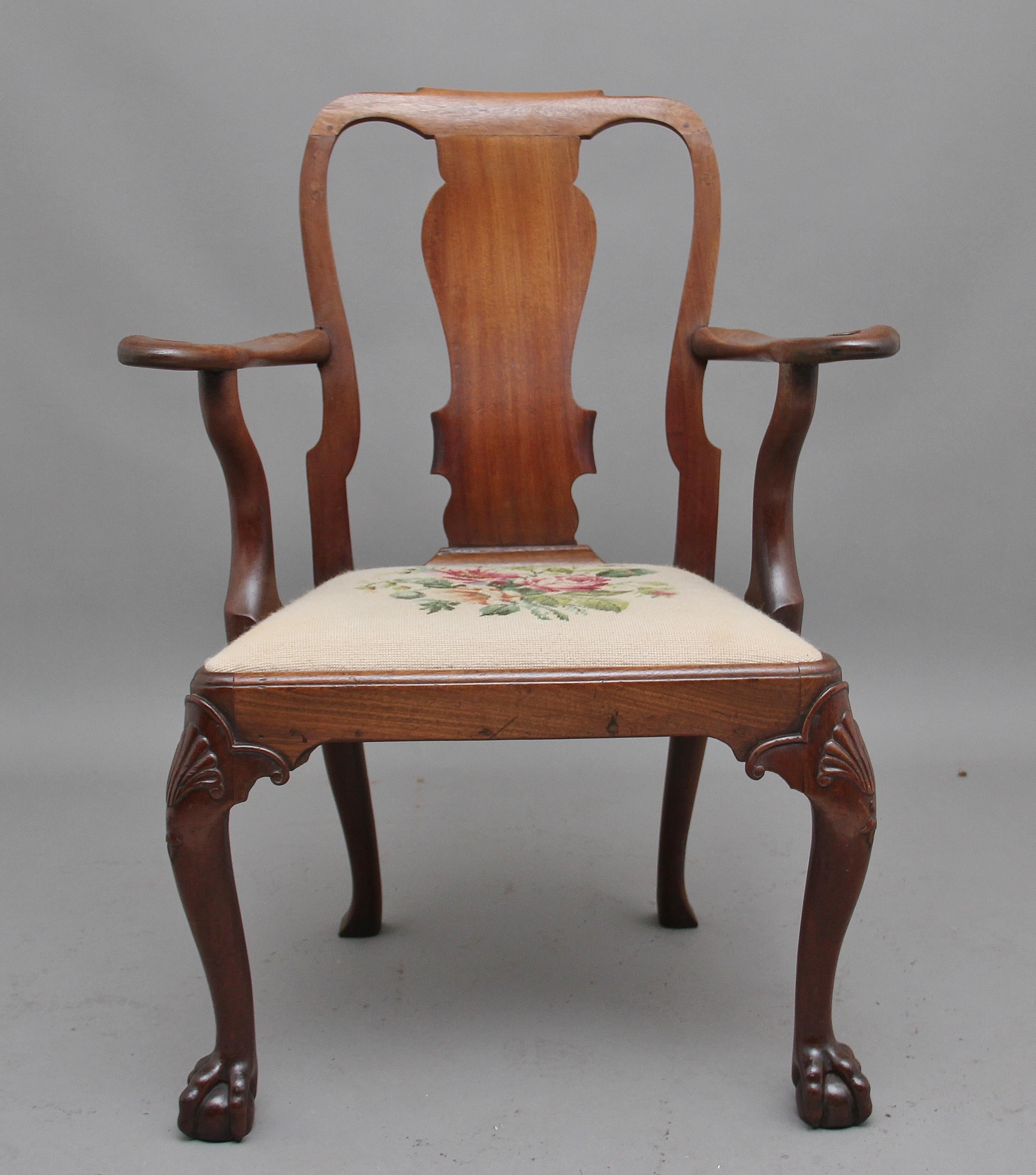 18th century walnut open armchair in the Queen Anne style, having a shaped central splat flanked by curved uprights, the elegantly shaped arm supports incorporating swan heads, drop in upholstered seat with a needlework floral pattern, standing on