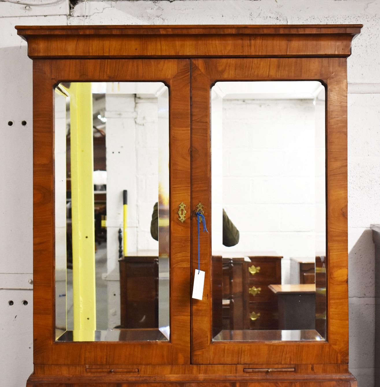 For sale is a good quality George II figured walnut bureau bookcase. The bookcase has an out swept cornice, above a pair of beveled mirror doors opening to reveal adjustable shelves, with two candle slides below, above a fall front. The fall opens