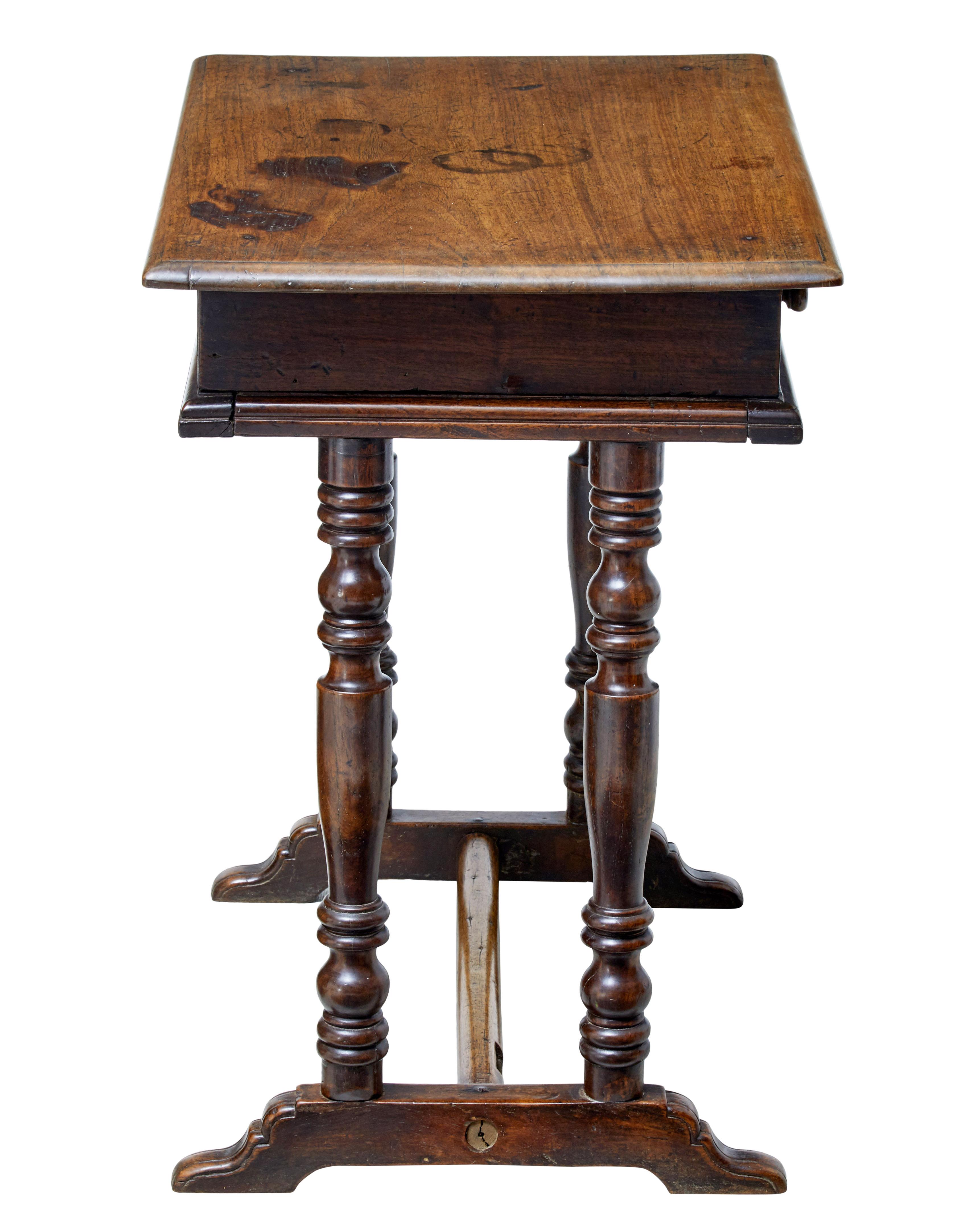 Quirky rustic walnut side table, circa 1780.

Oversailing top beneath which is a single drawer with two turned handles

Standing on four turned legs and sledge feet, united by stretcher.

Lock missing to drawer, surface burns and staining to