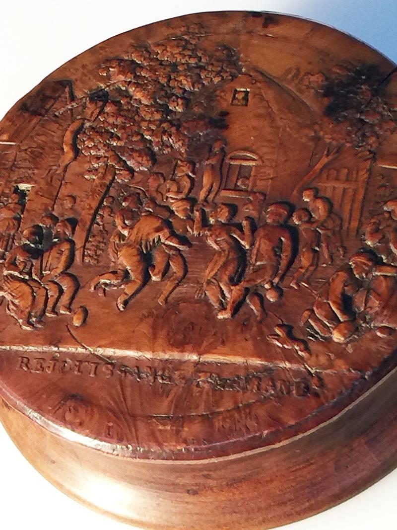 18th Century French walnut wooden snuffbox 

French walnut wooden snuffbox 
Beautiful detailed cut scenery, celebrating people
The text will be probably 