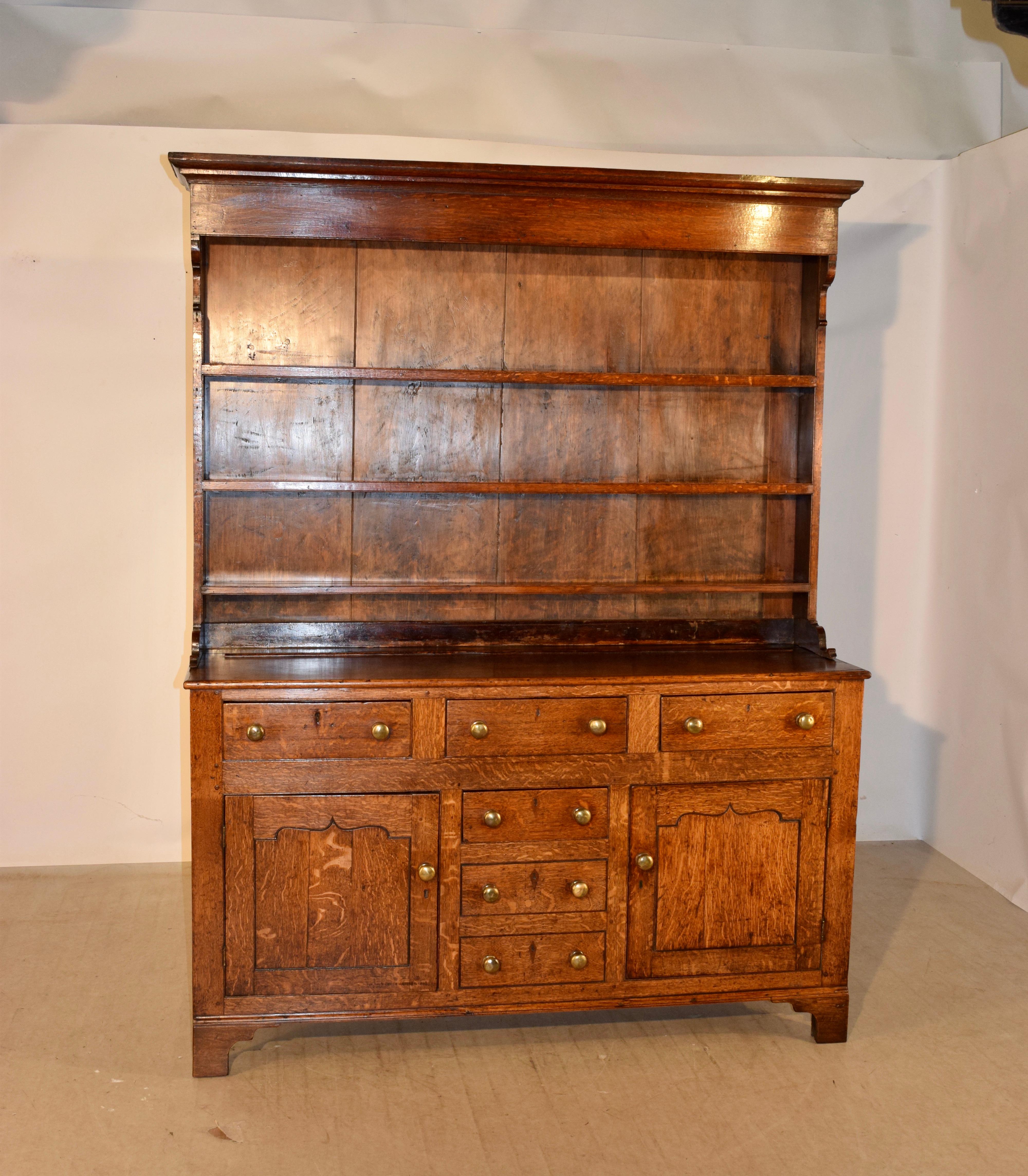 18th century welsh dresser made from oak. It has a wonderful crown over three shelves atop a lovely base with paneled sides and three drawers in the front over two raised paneled doors, which flank three  central drawers. The bottom two drawers are