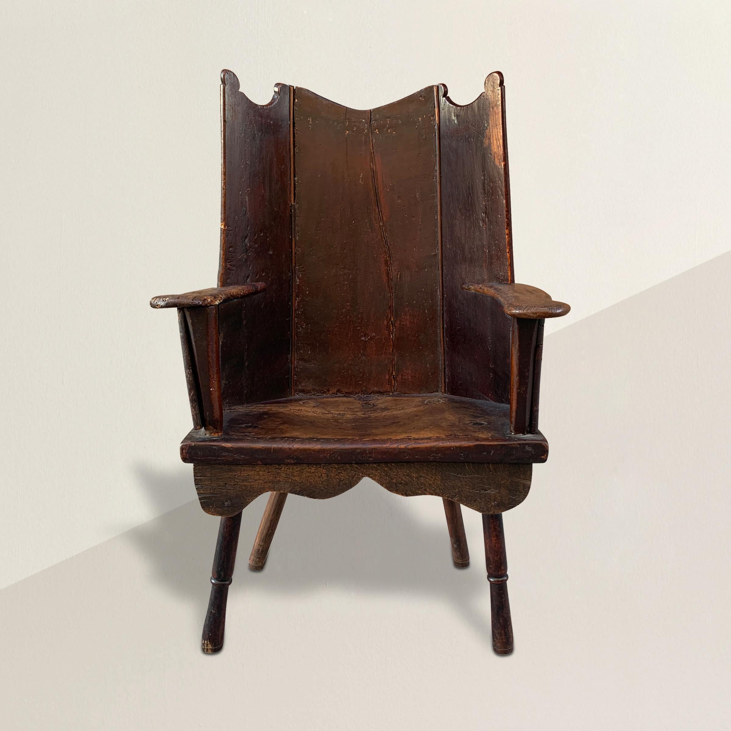 An extraordinary 18th century Welsh oak wingback lambing chair having a back constructed of three oak panels with scalloped top, and straight flat arms with rounded ends, through turned front legs and more recent back legs. Lambing chairs were