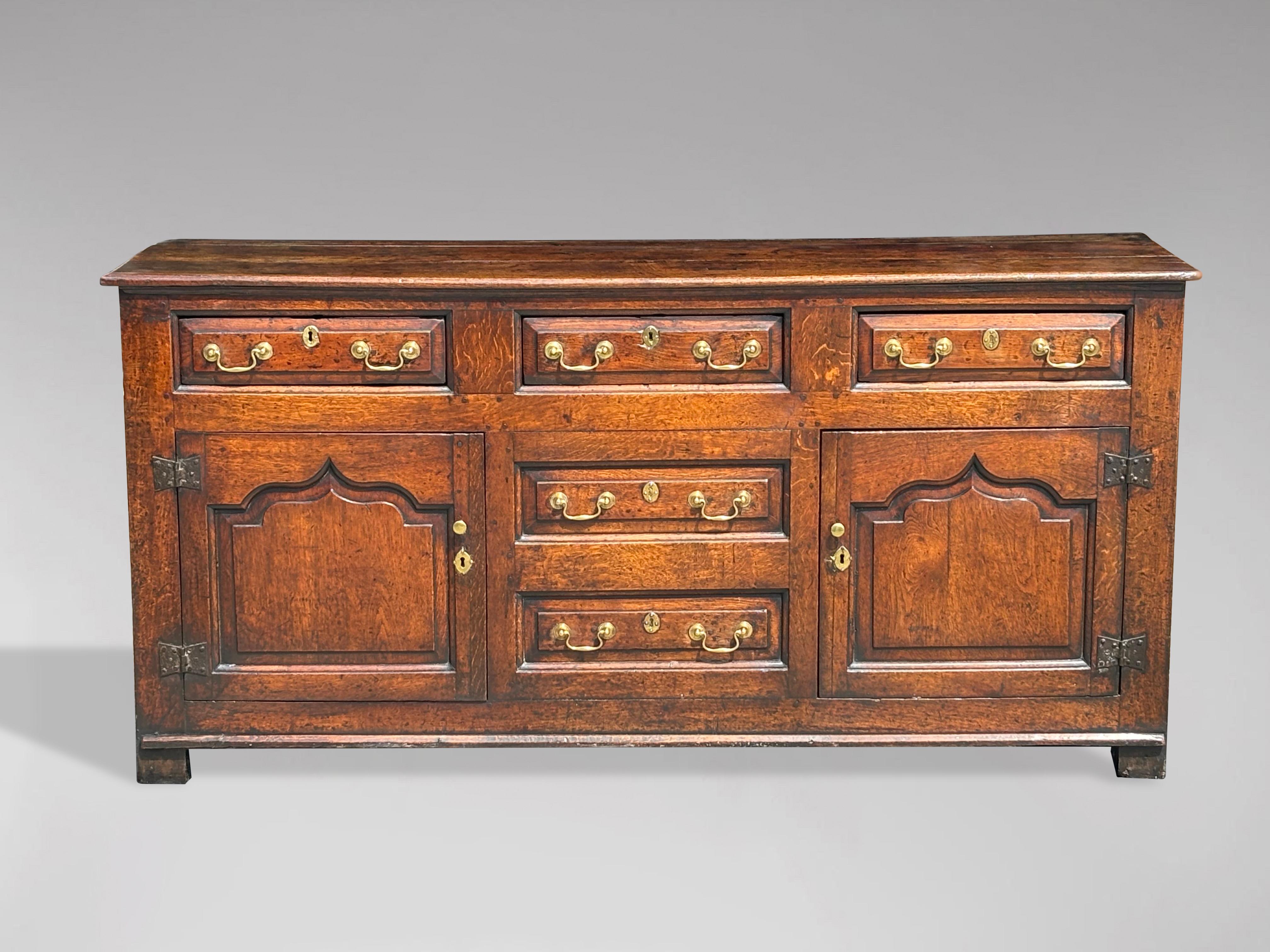 A stunning mid 18th century large oak Welsh dresser base cupboard. Well figured oak moulded top above three frieze drawers with an arrangement of two further central false drawers flanked by panelled cupboard doors opening to reveal shelves. Moulded
