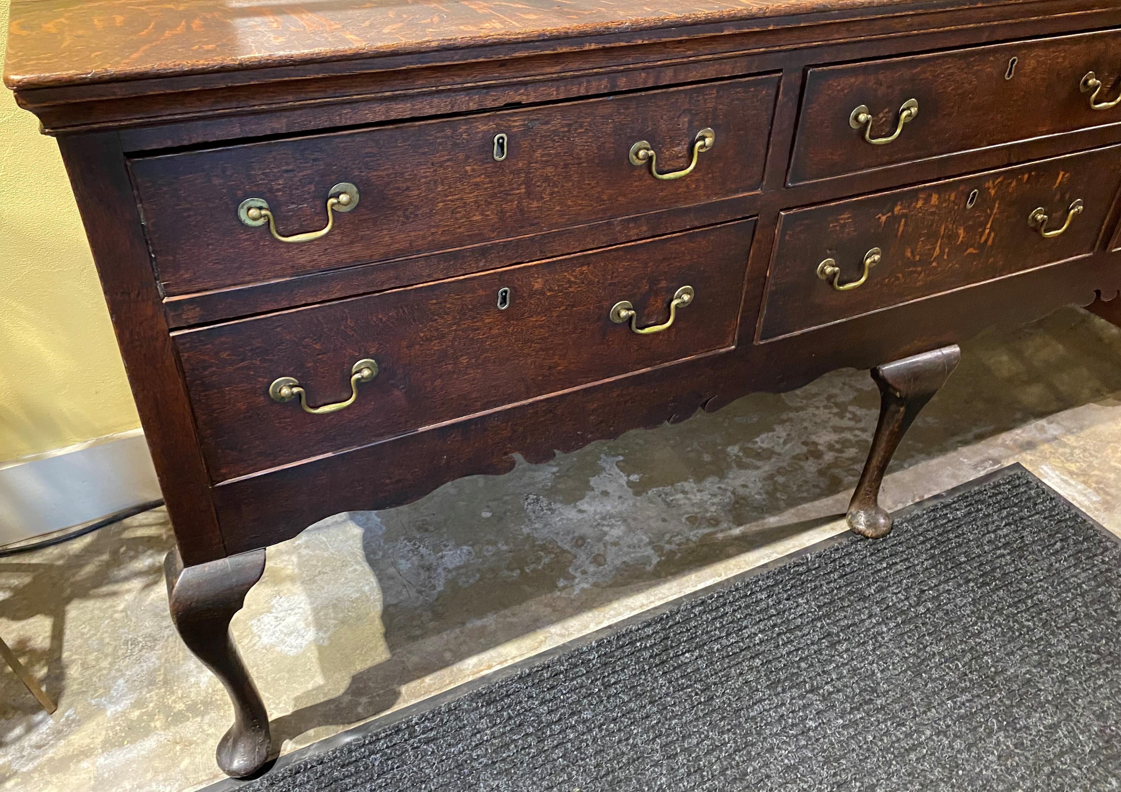 A fine Welsh oak dresser base or server with a rectangular molded edge top surmounting a case with six fitted drawers, over a shaped skirt, all supported by three front cabriole legs terminating with pad feet, and two rear cabriole shape legs