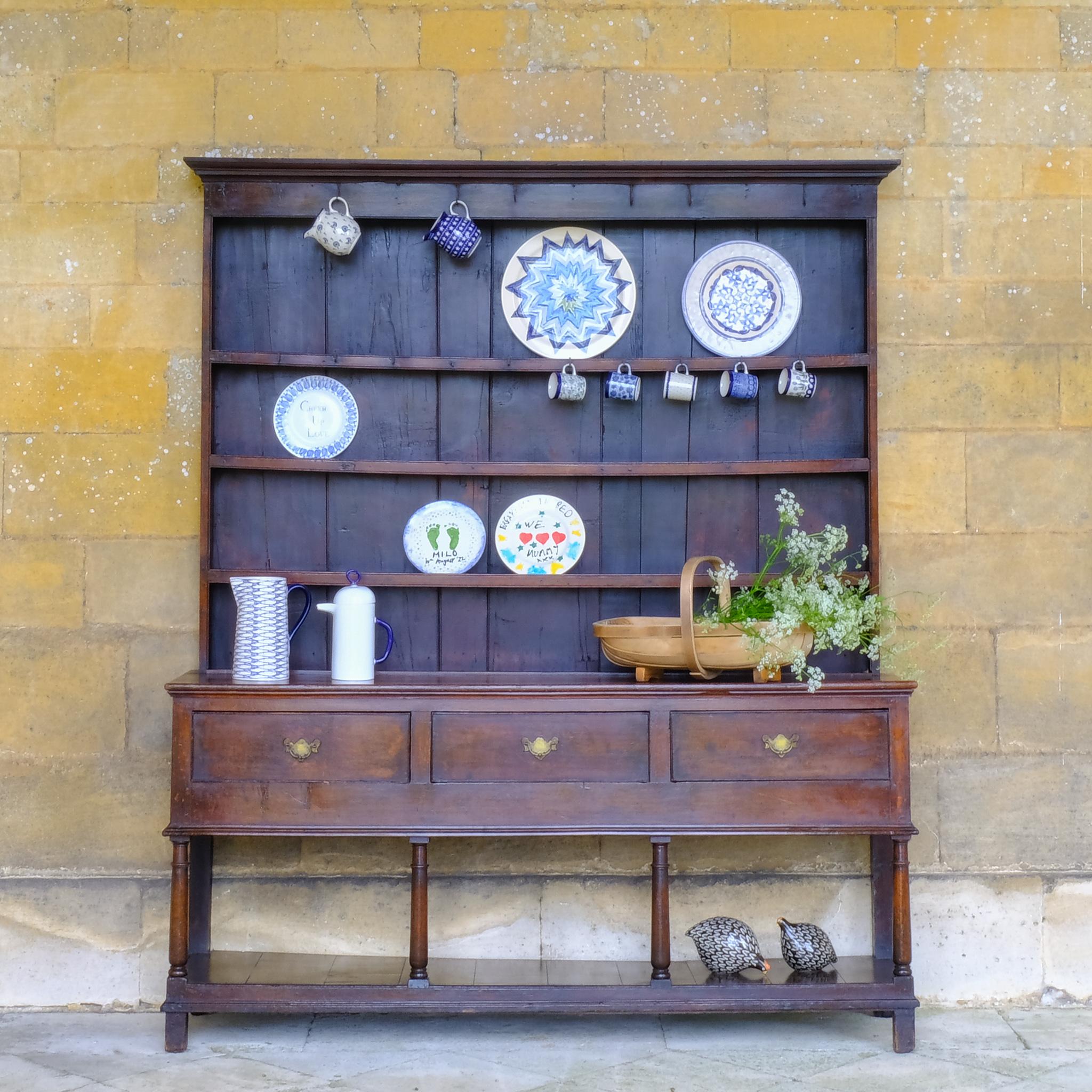 A large 18th century Welsh oak dresser in a beautiful, rich colour, with boarded plate shelves over a three drawer base raised on four elegantly turned supports with a boarded lower shelf. Various hooks along the upper shelf and top. Comes in two