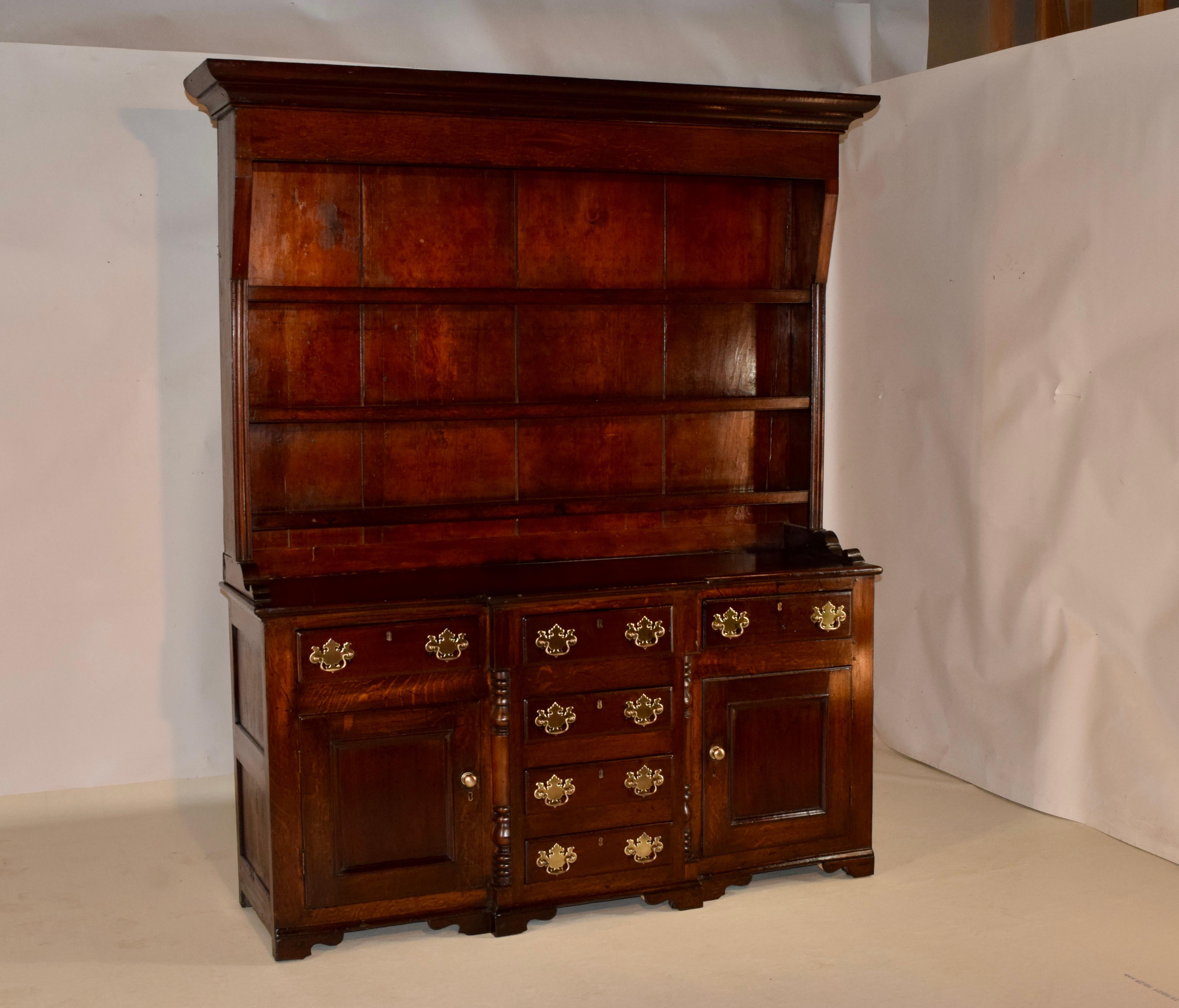 18th century Welsh oak dresser from England. The piece has lovely rich color and wonderful graining throughout. The crown sits atop gorgeous wide backboards which hold three upper shelves, over a fabulous base with two single drawer s over single