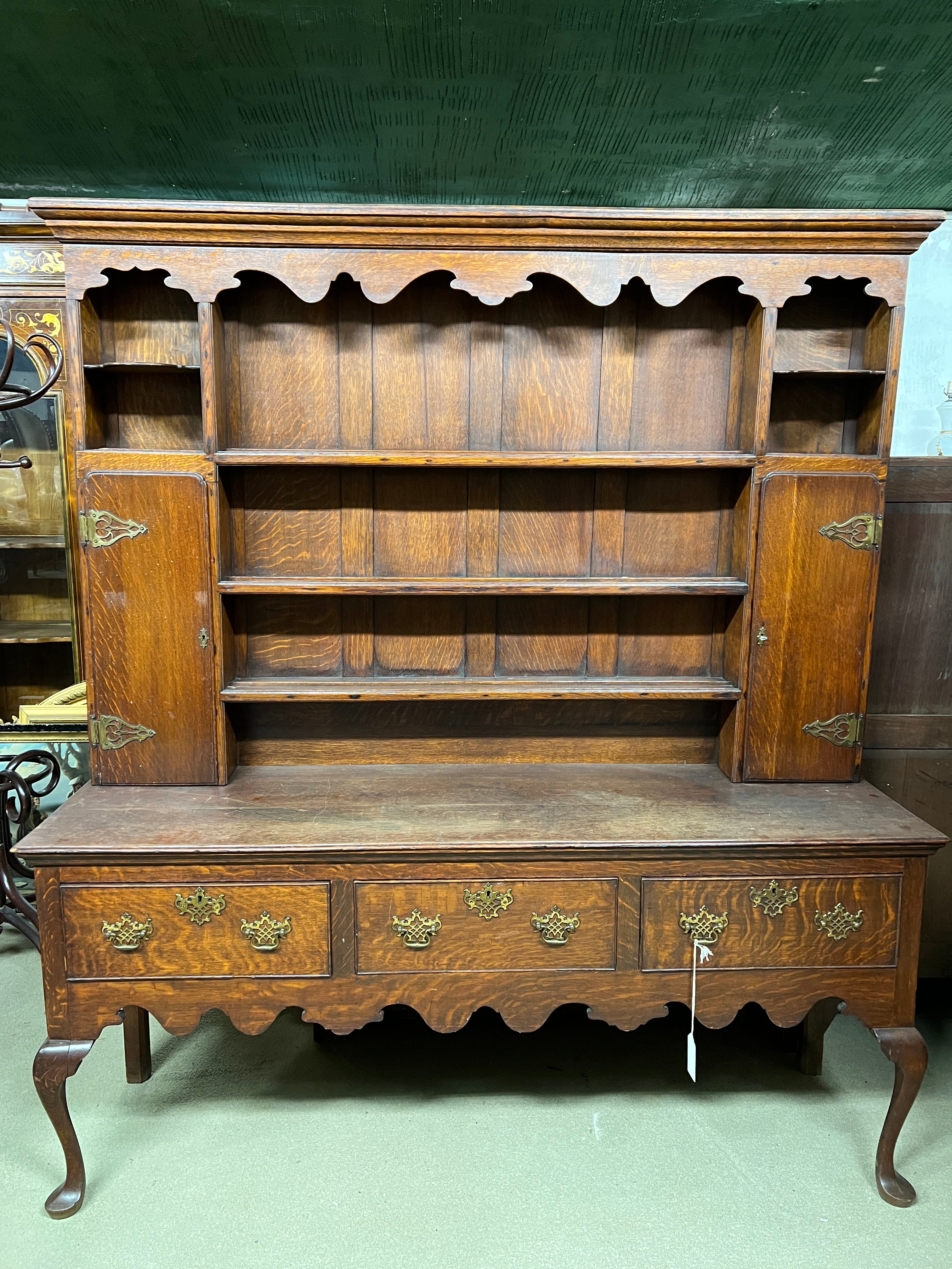 This 18th-century Queen Anne-style oak dresser and rack is an impressive rustic and functional piece of furniture that can bring a touch of family history and domestic warmth to any home. 
This type of furniture was typical of the British