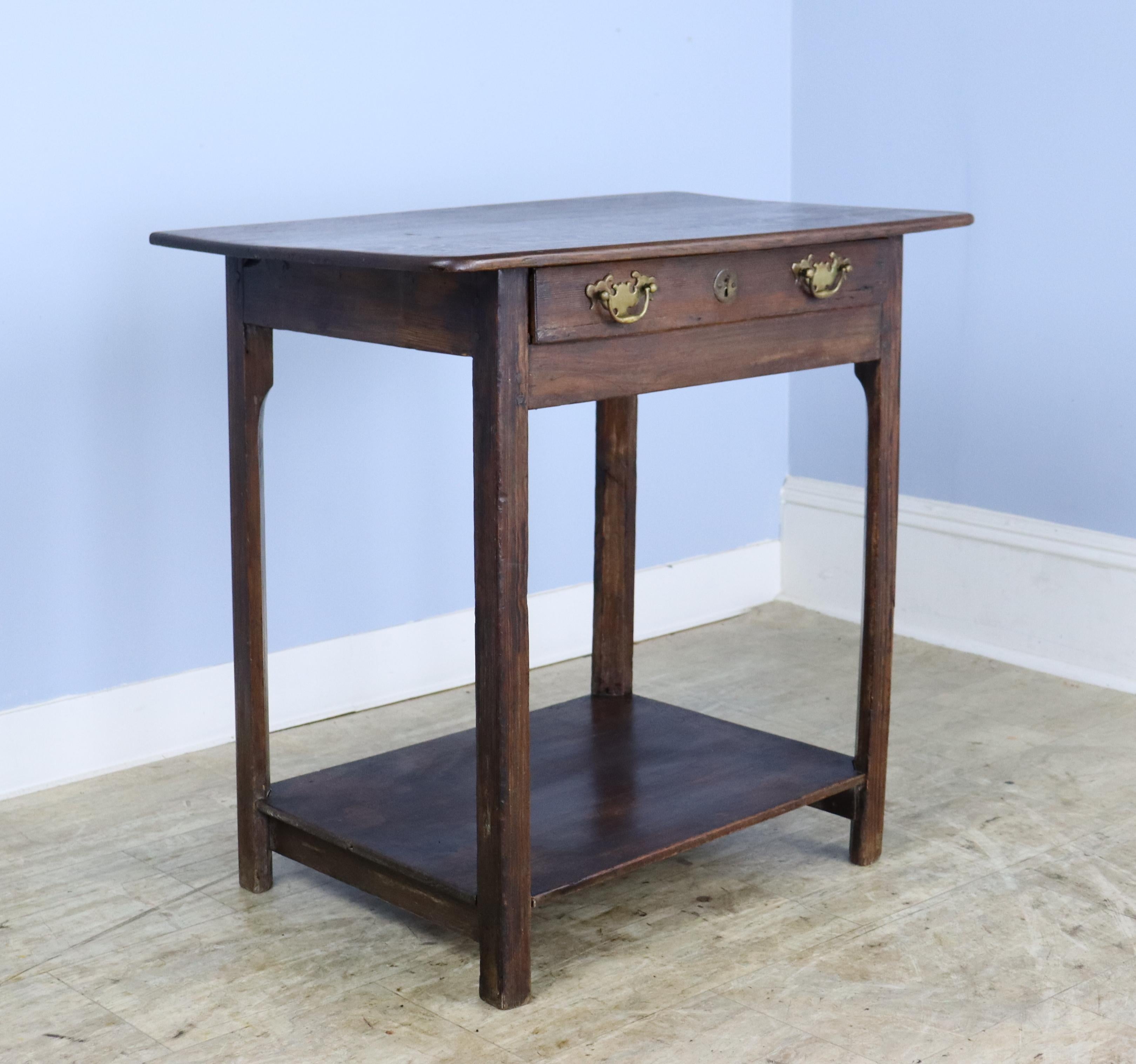 A charming, very early pine side table with a polished oak top.  Single shallow drawer with original brass ecutcheons and a low potboard complete the look.
