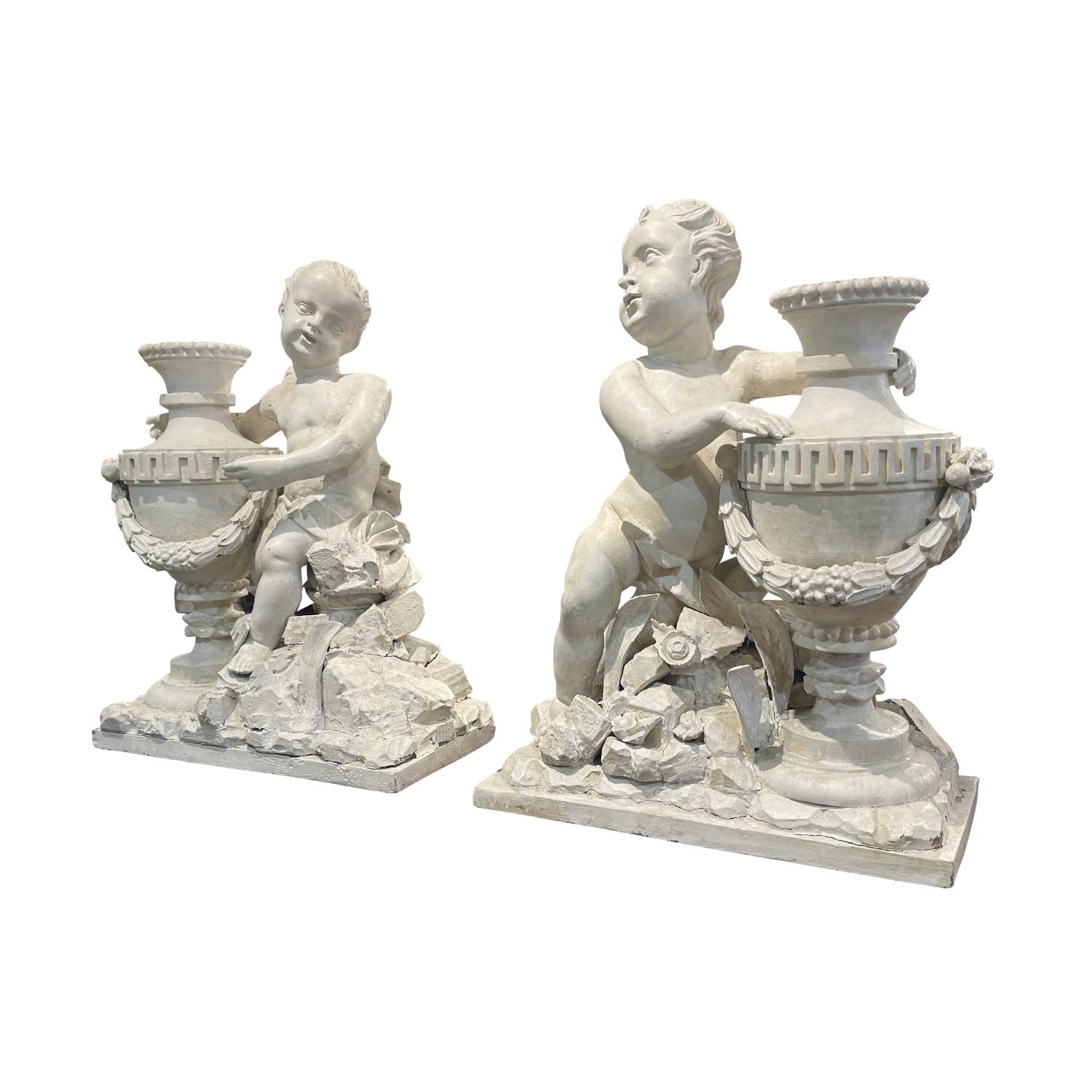 Paire de statuettes Putti ou Chérubins de l'époque Louis XVI, de couleur blanc-gris. Sculptés à la main et patinés en noyer dans leur état d'origine antique. Cette paire de putti parisiens se font face et sont élégamment drapés autour des hanches.