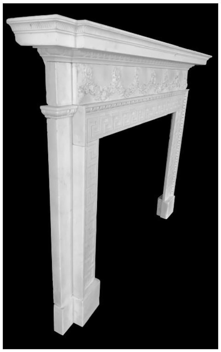 A well carved 18th century, English Regency antique fireplace mantel in the Greek Revival manner. Boldly carved in white statuary marble with a carved reeded moulded shelf over the panelled frieze which has carved grapevine and foliage leaves across