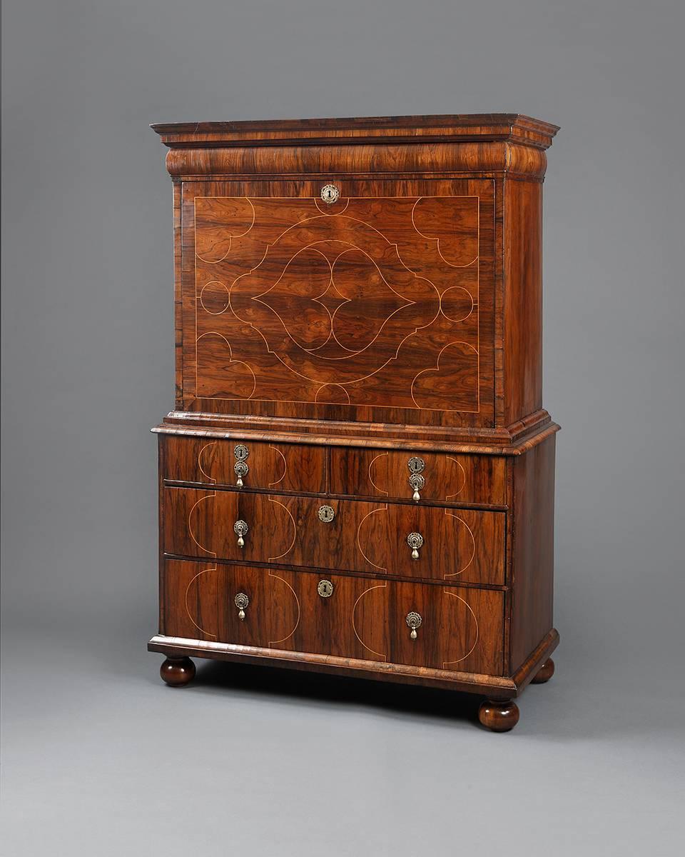 An early 18th century fall front writing cabinet or escritoire. Beautifully veneered in Princes-wood (rosewood) with geometric designs of holly throughout the front. It is constructed in two parts with the upper section containing a hidden frieze