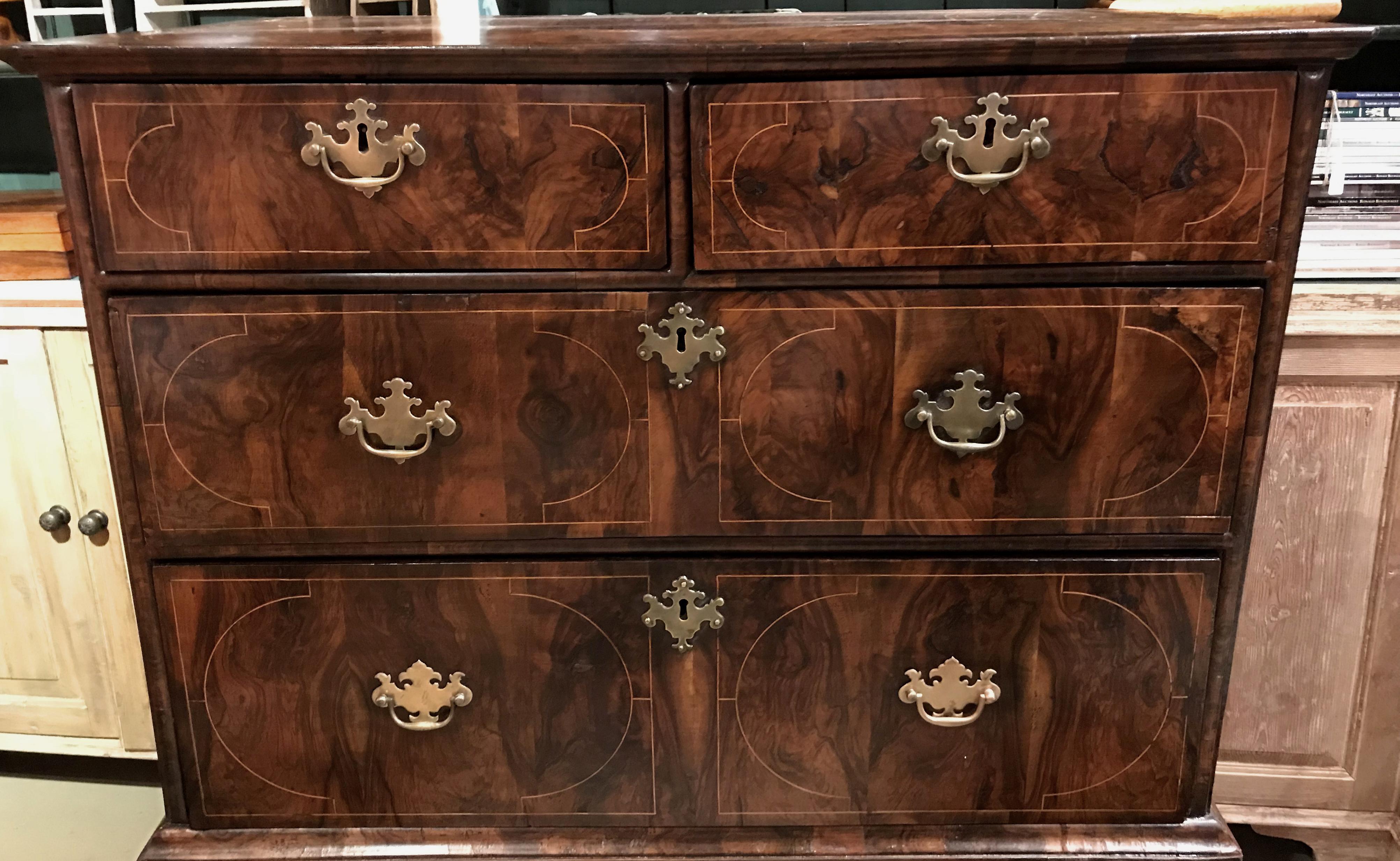 A good example of a William & Mary walnut veneered chest on stand, the upper case with a rectangular line inlaid top with molded cornice, surmounting two fitted small drawers over three long drawers adorned with demilune and rectangular line inlay