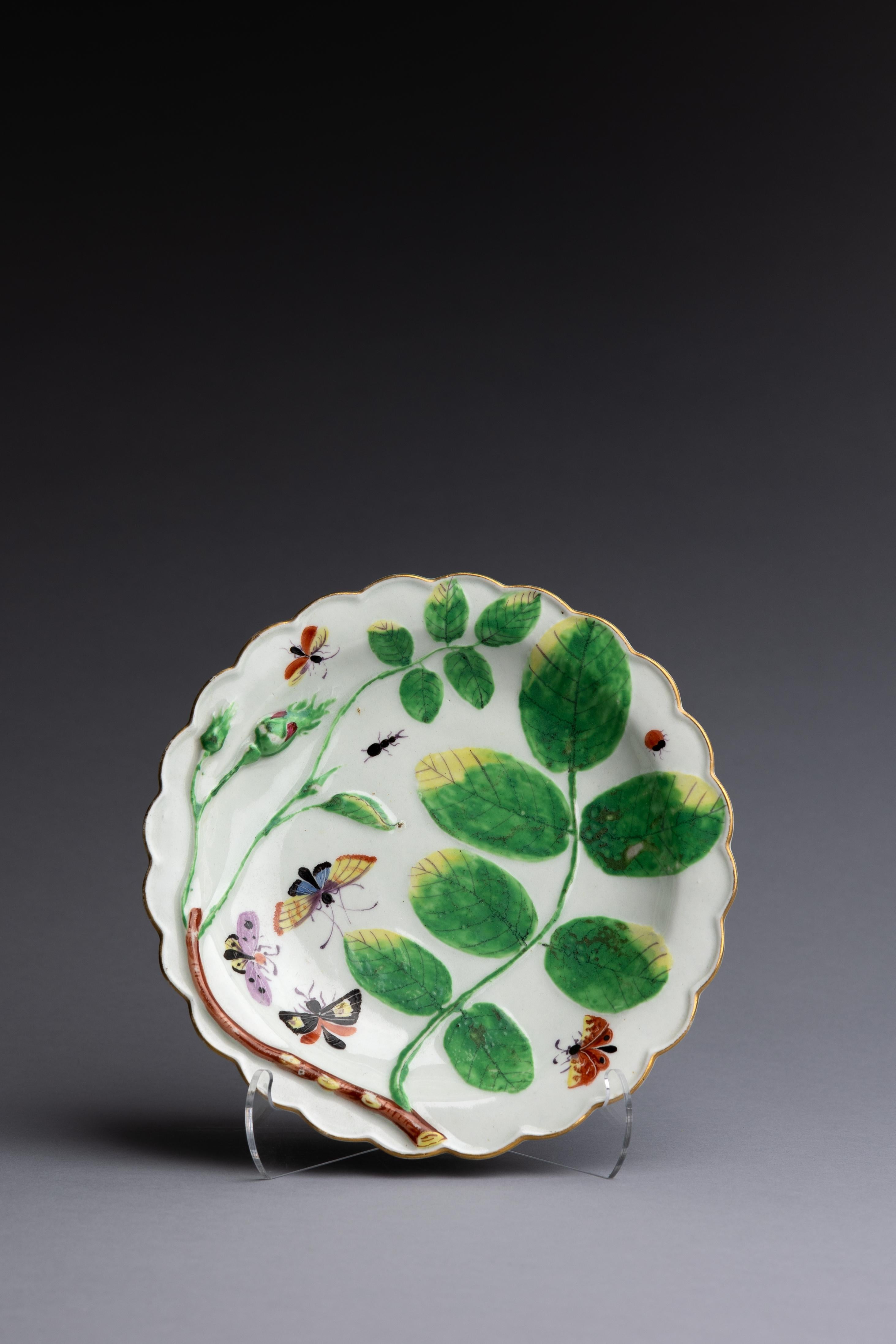 Assiette en porcelaine de Worcester Blind Earl, fabriquée vers 1770, avec un magnifique décor émaillé de papillons et d'insectes parmi des feuilles en relief et des boutons de rose, le tout entouré d'un bord festonné délicatement doré.

En 1780,