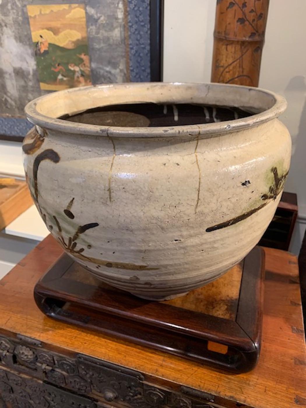 18th century wax bean pot from the Kyushu prefecture and the famous Yumino kiln. Handsome pines decorate the white slip glaze. Old kintsugi repair in gold, highlights this pots simple elegance.