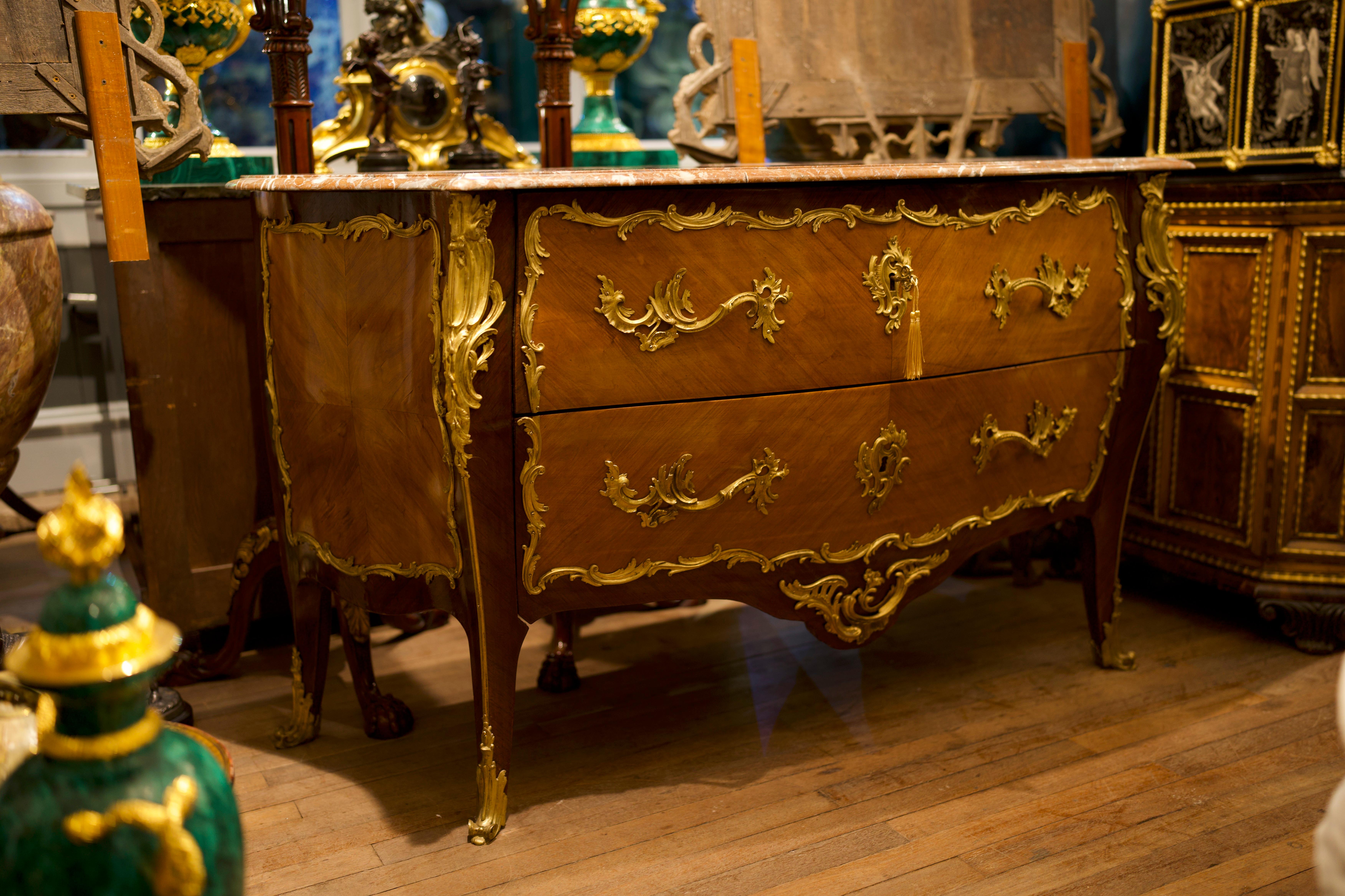 18th century marble-top bronze mounted Kingwood Louis XV Commode.

Spectacular custom quality commode with full bronze shoes leading to a myriad of bronze trim work and floral inlays of kings-wood and satinwood design. The marble top supported by