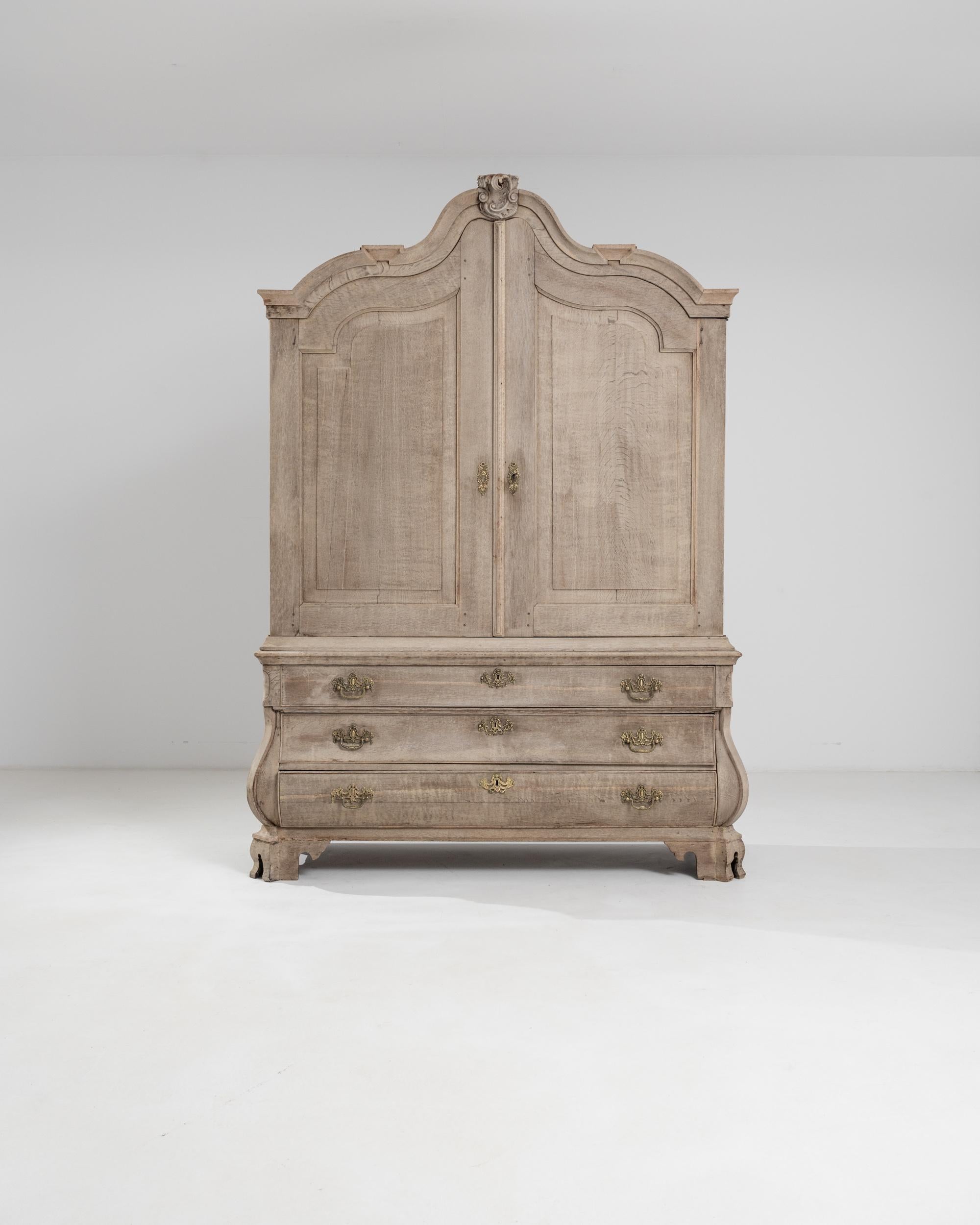 An 18th cabinet made in the Netherlands, this statuesque piece flaunts an elegant baroque silhouette. Standing on molded ogee bracket feet, the bombe chest is provided with three large drawers and a sculpted cornice top with a verdant central molded