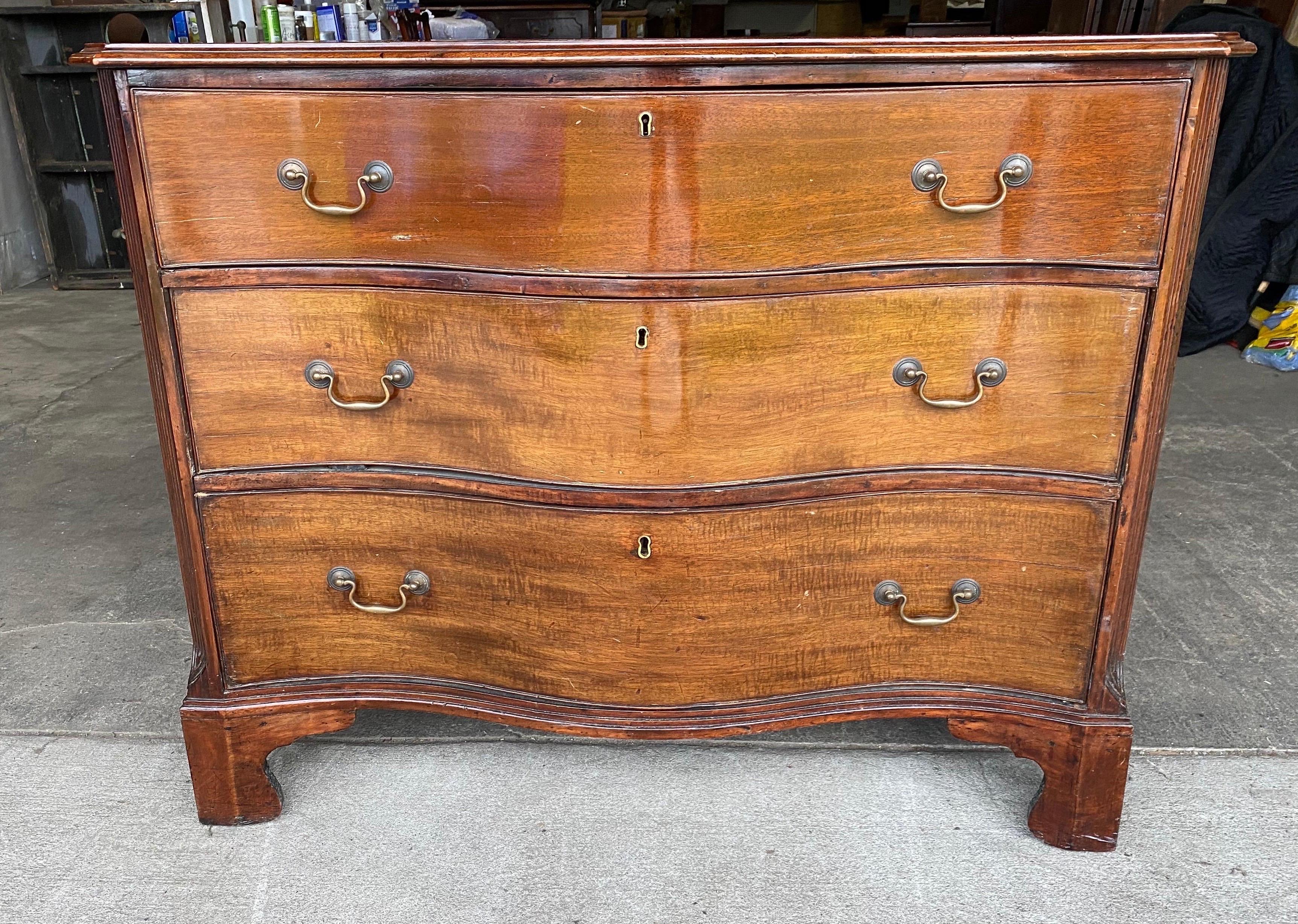 18th-early 19th century Georgian mahogany serpentine bedside chest with molded top, canted and reeded corners and bracket feet.