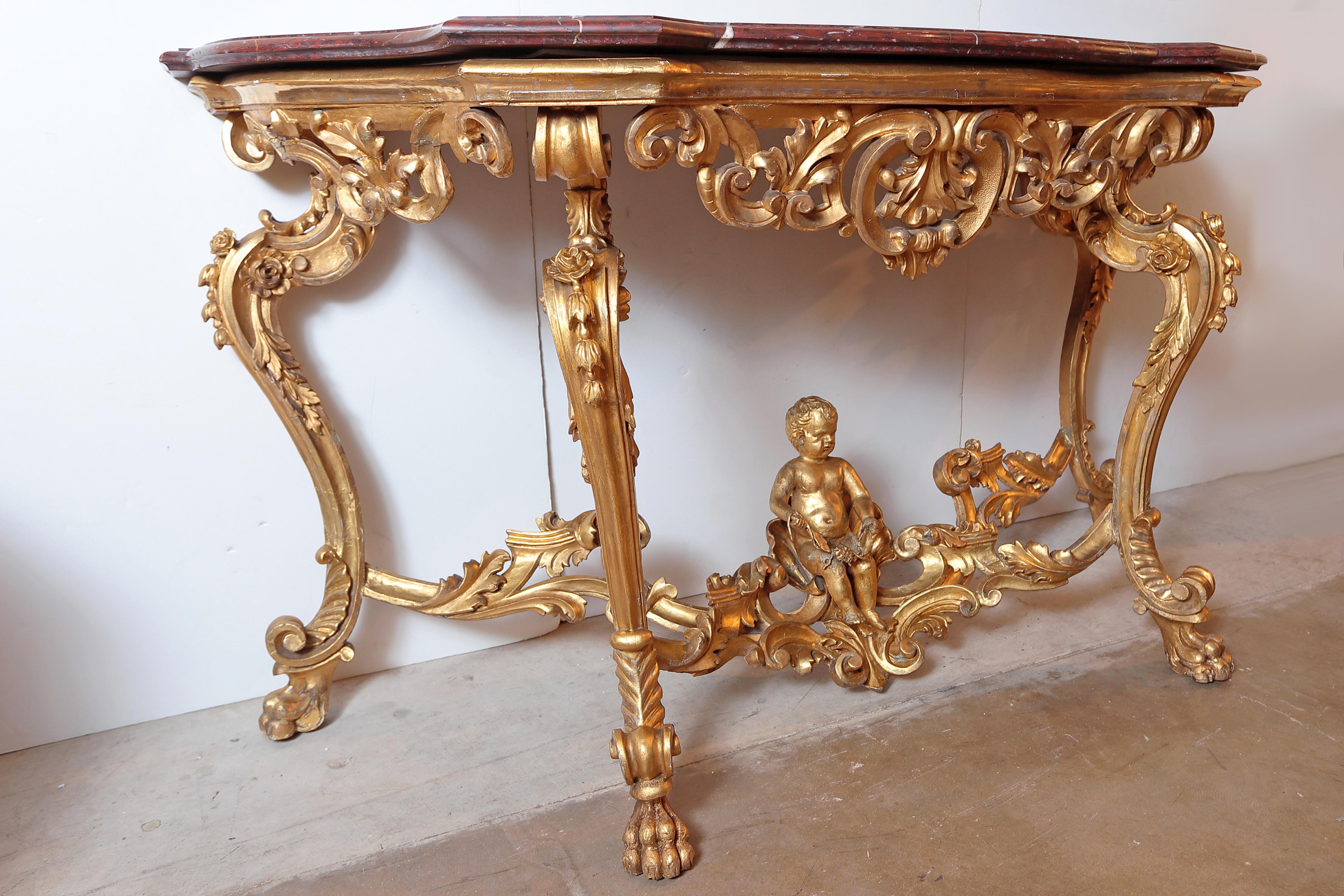 18th century French Louis XV carved console with the original water gilding. Finely detailed with elaborate carving and a large cherub on the stretcher base. The original Rosso marble top.