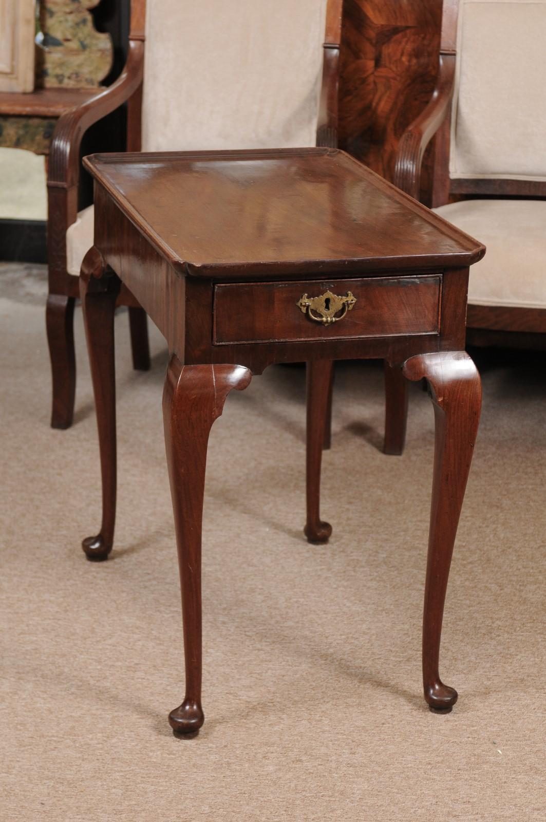 A George II 18th century Mahogany tea table featuring dish top, single drawer in frieze with cock beading boarding the drawer and with brass pull. The legs with cabriole form ending in pad feet.