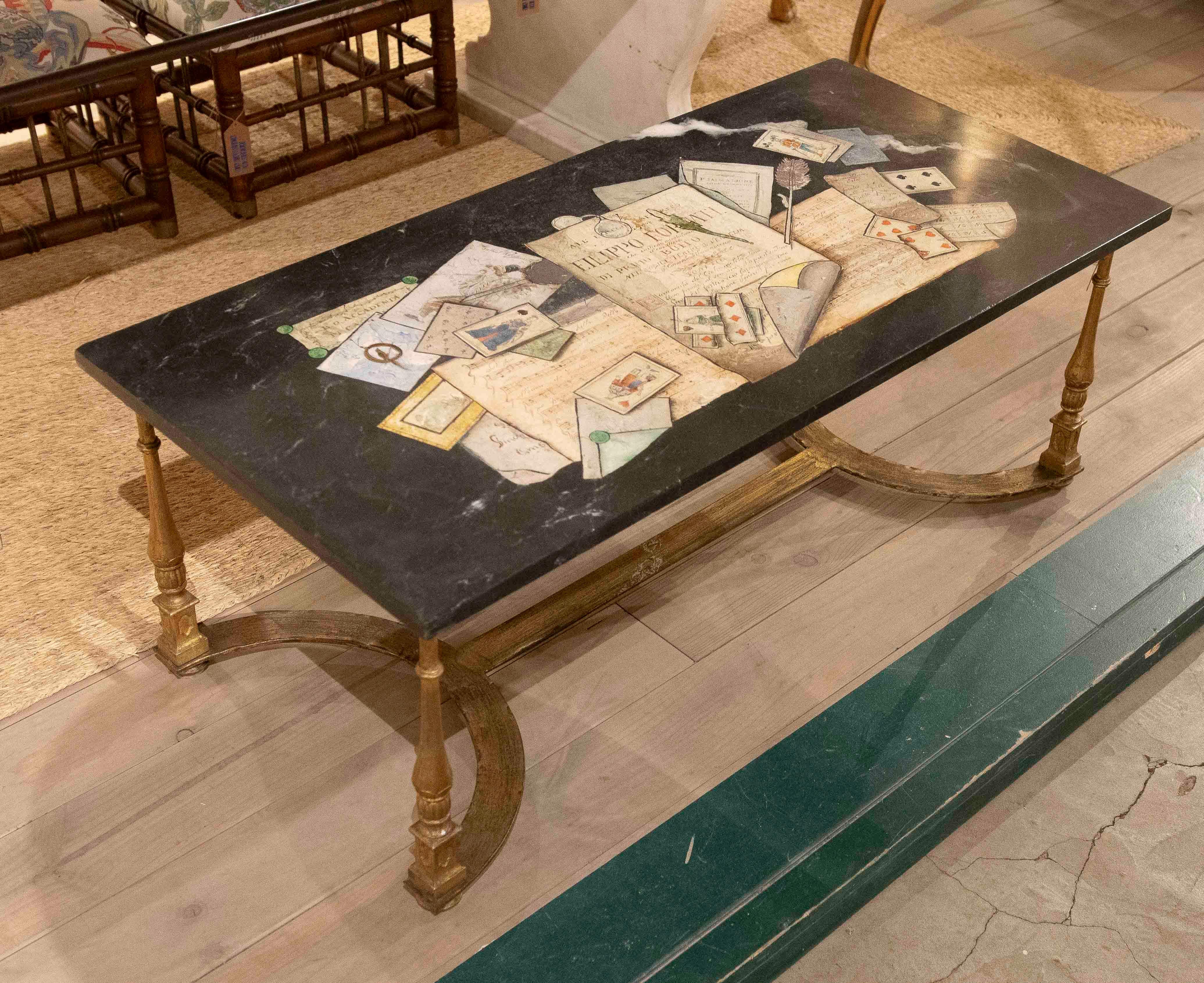Elegant coffee table with a black stucco top decorated with hand-painted trompe-l'œil inlays, depicting letters, envelopes, and stationery in a detailed and realistic composition. The paintwork stands out for its meticulousness and three-dimensional