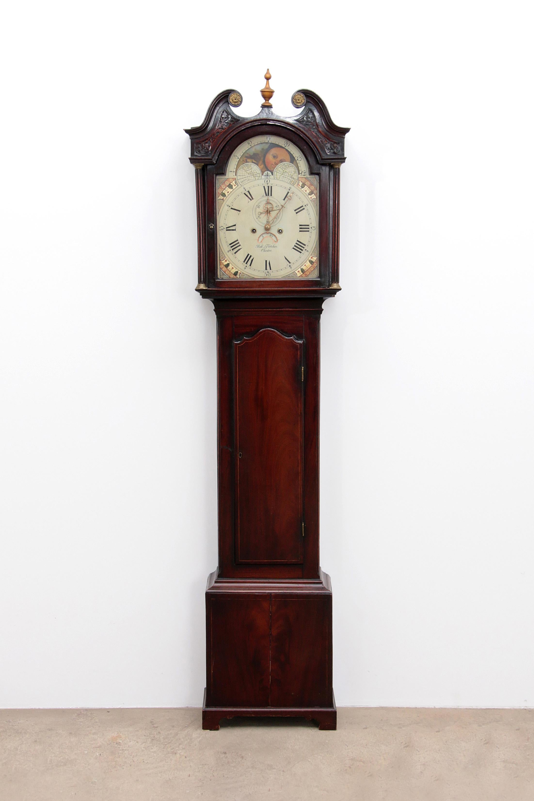 This 18th-century mahogany longcase clock boasts a beautifully painted 13-inch arched dial, featuring a charming sun and moon automaton on the arch, a subsidiary seconds dial, and a date window. The movement strikes a bell, and the case includes
