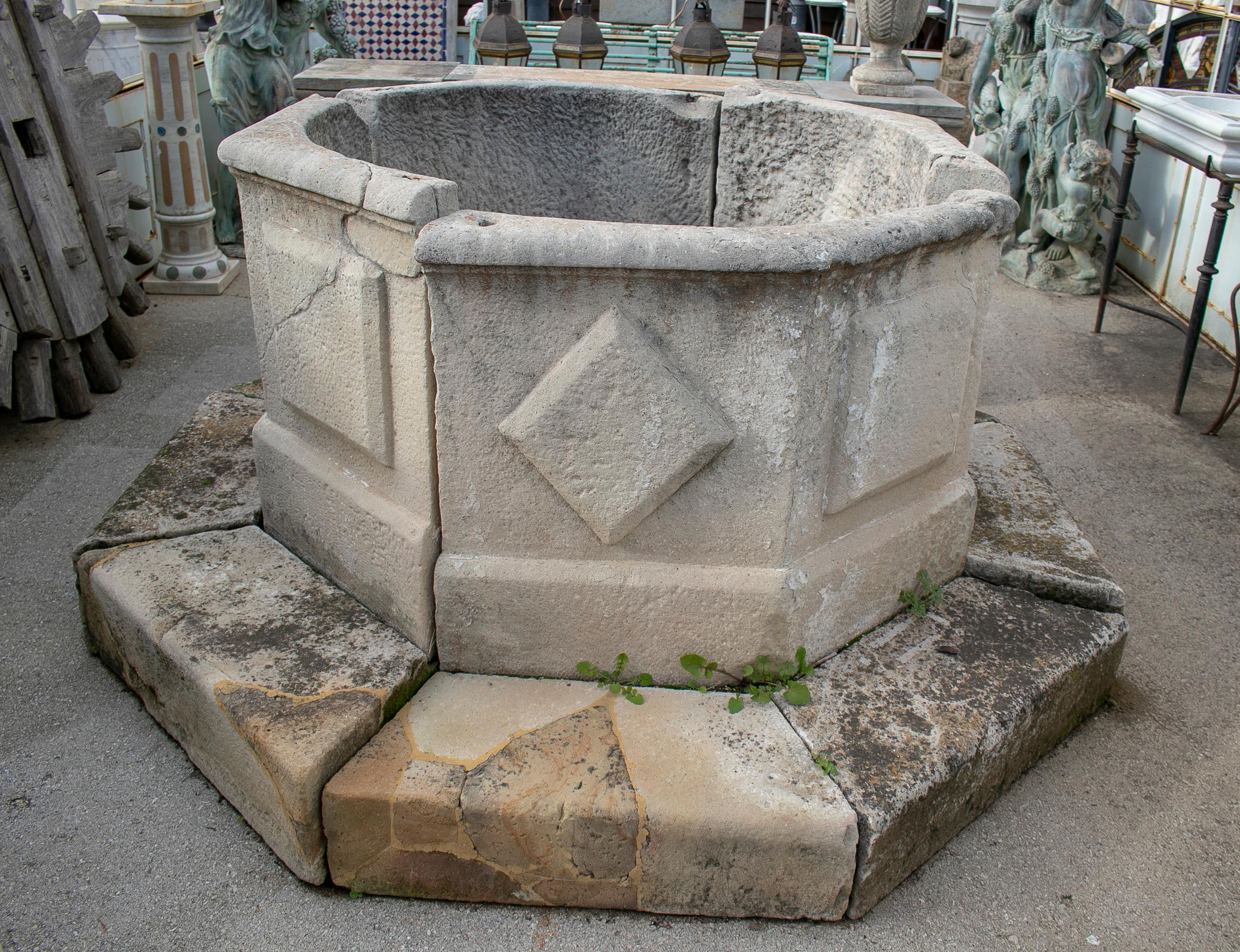 19th octagonal stone wellhead with family emblems and inscription.