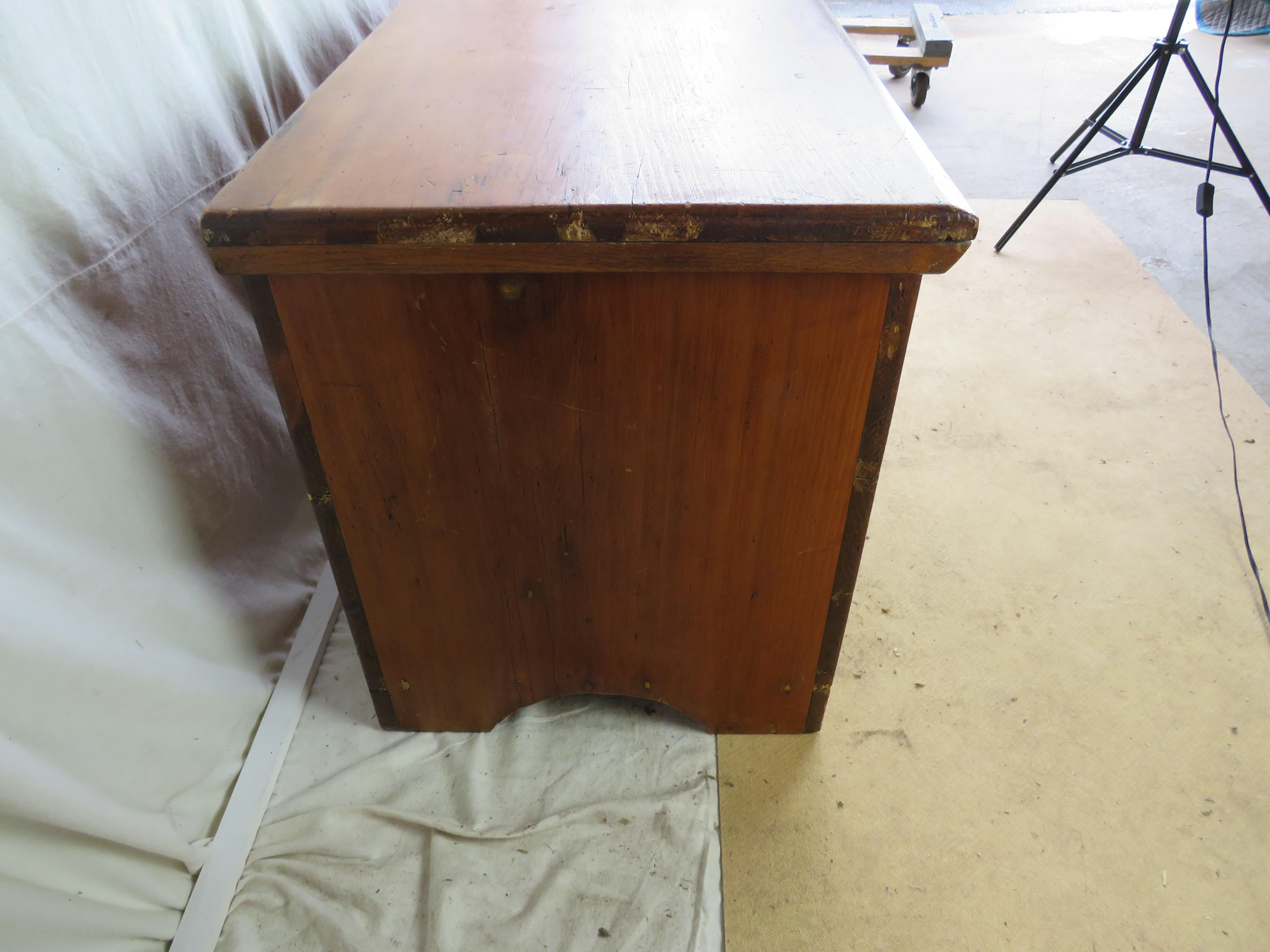 18th or Early 19th Century New England Pine Grain Bin in original red stain, having a rectangular lid held by long strap hinges, above five board case with interior divided into three sections, raised on bracket feet.

Chest remains in great