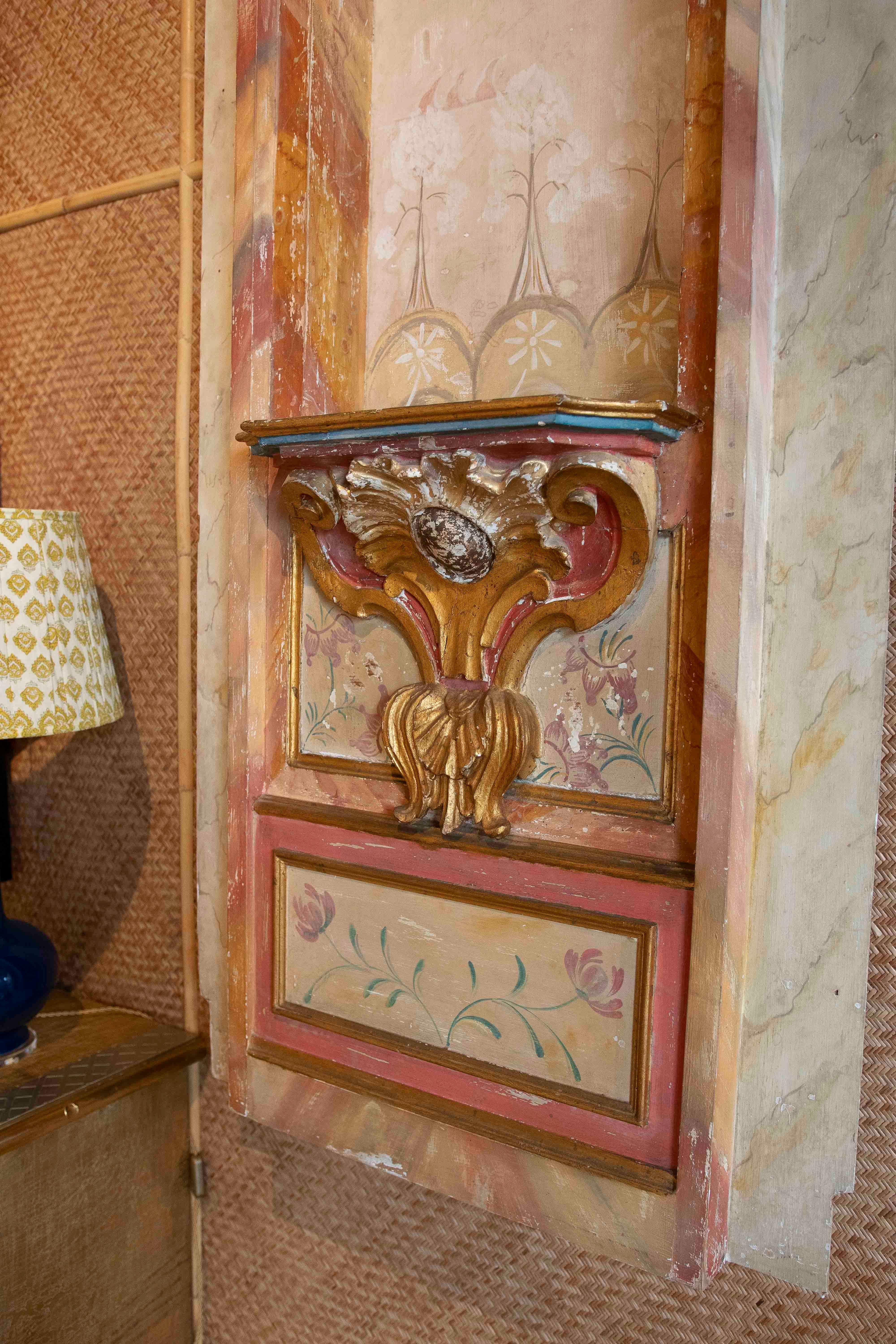 An elegant pair of carved, gilded, and polychrome wood wall niches with a central shelf and interior pictorial decoration featuring floral and landscape motifs. The pieces retain their original patina, with slight wear that enhances their
