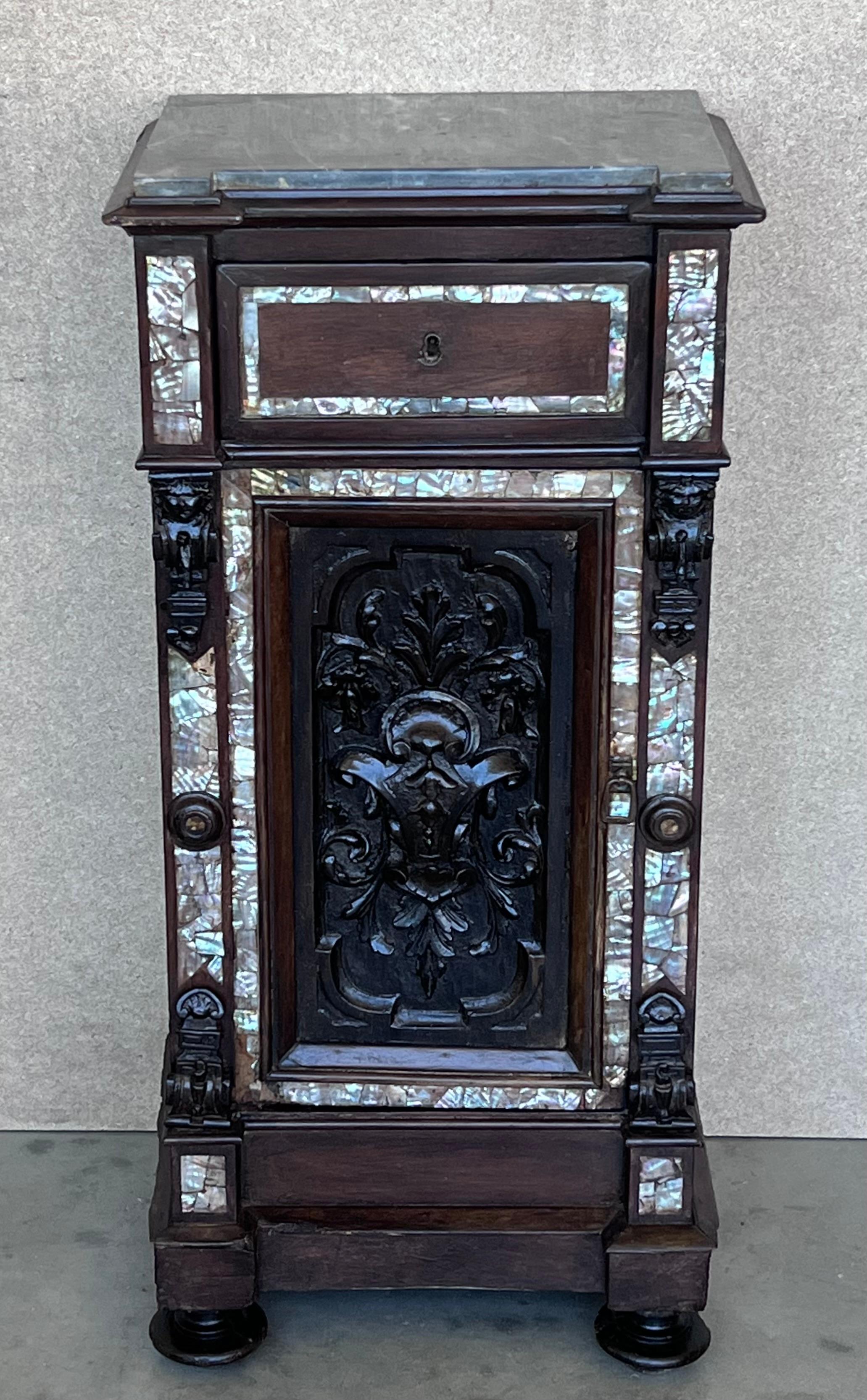 These elegant, antique bedside tables were created in Spain, circa 1800. Both matching cabinets are made of solid walnut; they have a recessed center carved door flanked by a pair of inlay columns supports decorated with carved reliefs both at the