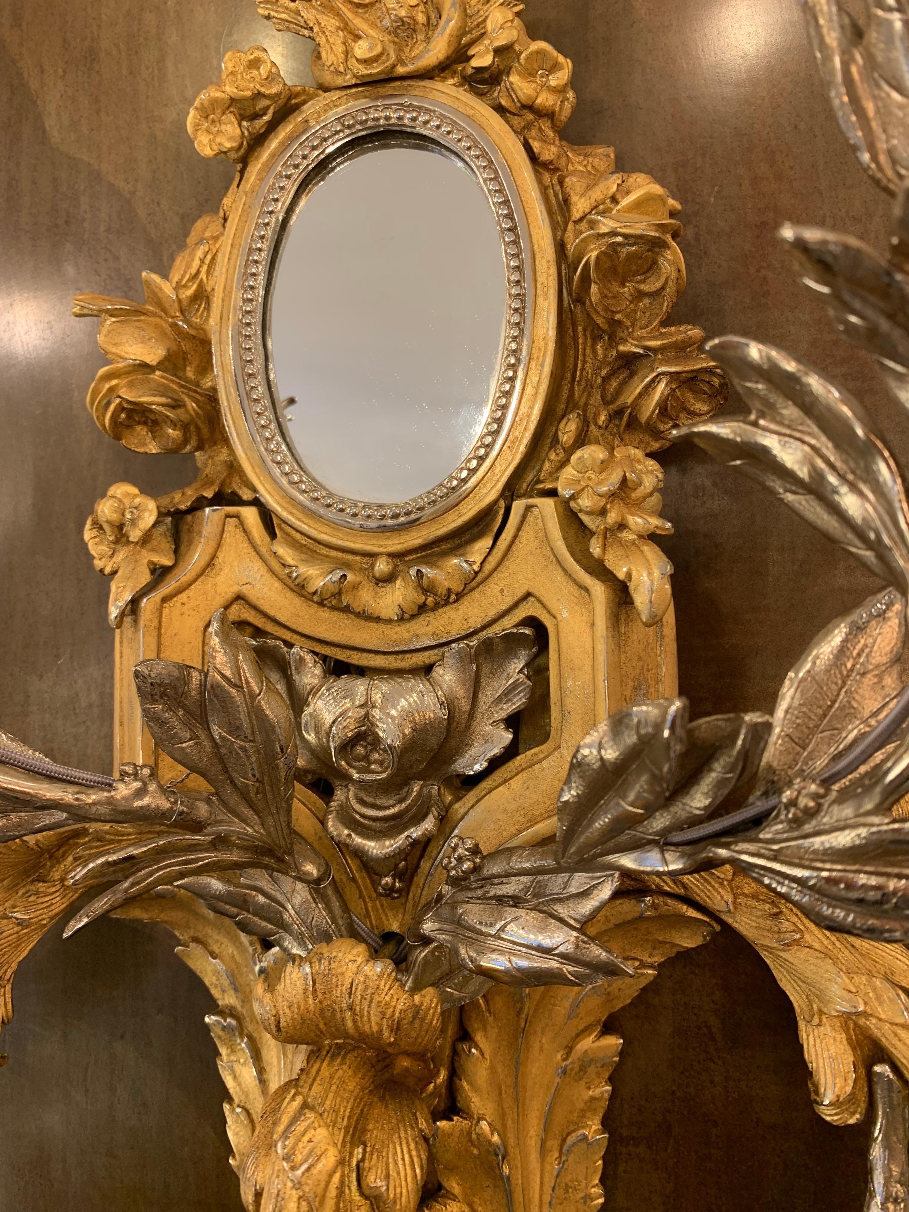 This sconce skillfully blends several motifs and influences of the great goldsmiths of the eighteenth century.

The mirror on the one hand, which is a reminder of the evolution of lighting at the time. Indeed, the arms of light are imposed at the