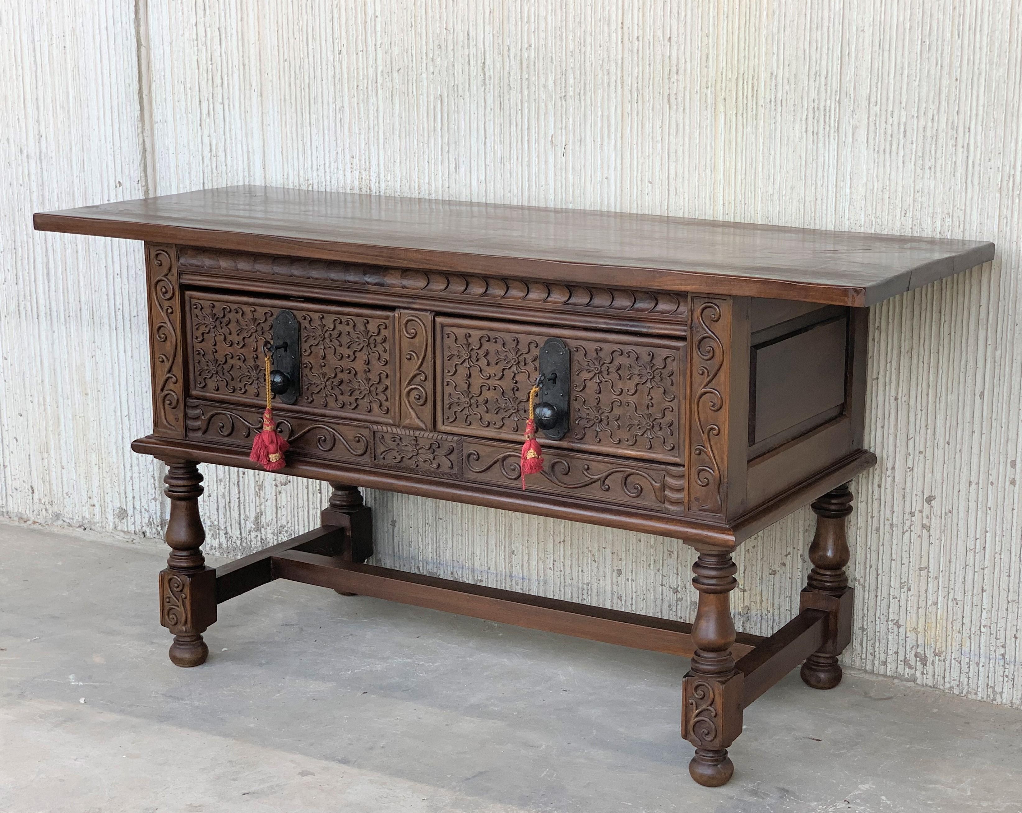 This large Spanish late 18th century features a beautiful one plank rectangular top over two carved drawers. Each drawer, featuring slightly different hardware, is adorned with geometrical motifs. Rosettes are carved between the drawers and each