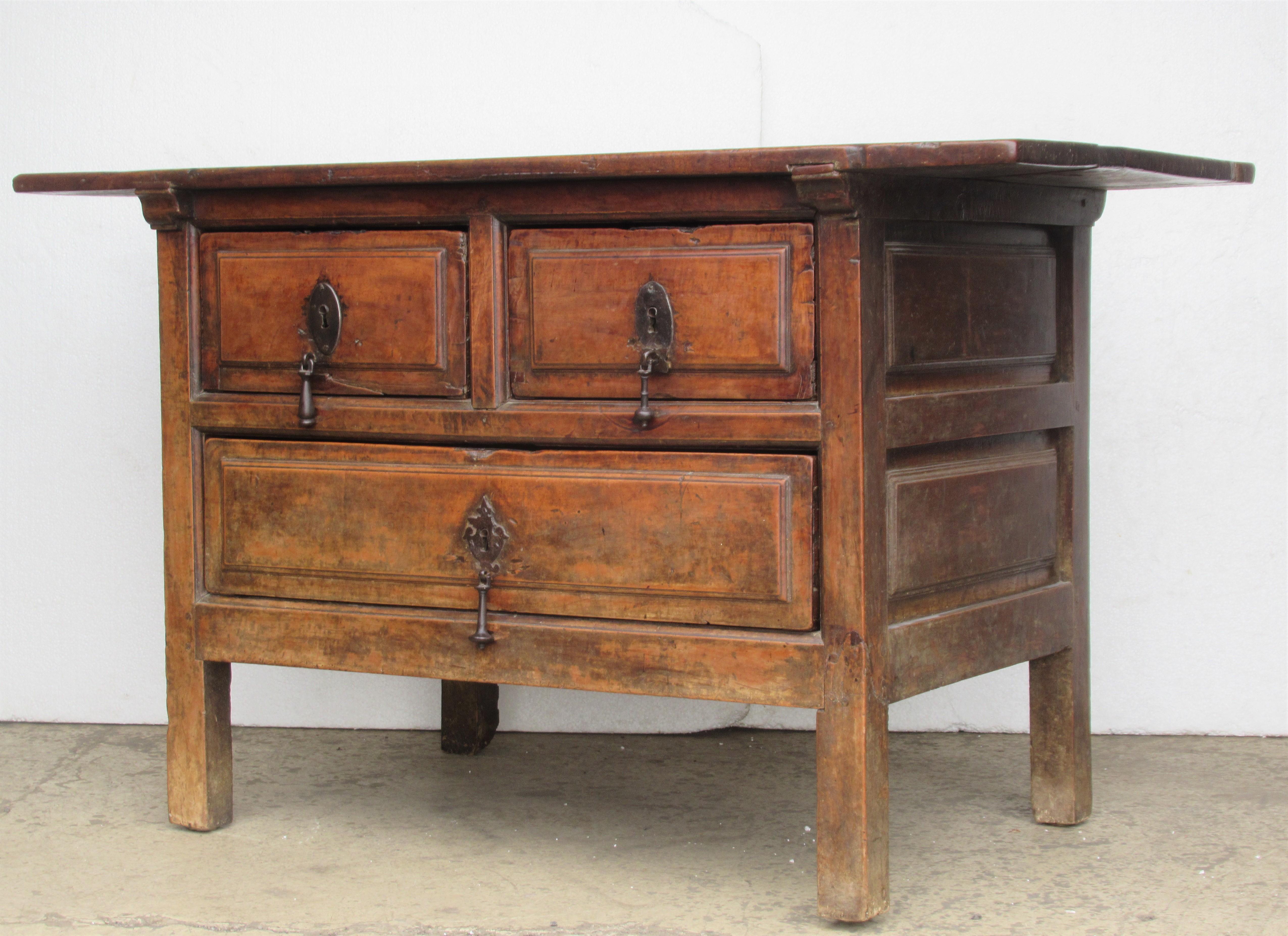 Antique Spanish walnut work table sideboard server with three very deep drawers (two short over long) wide over hanging plank board top, well detailed deep paneled sides and back. All early pegged and dovetail construction. Original fine hand forged