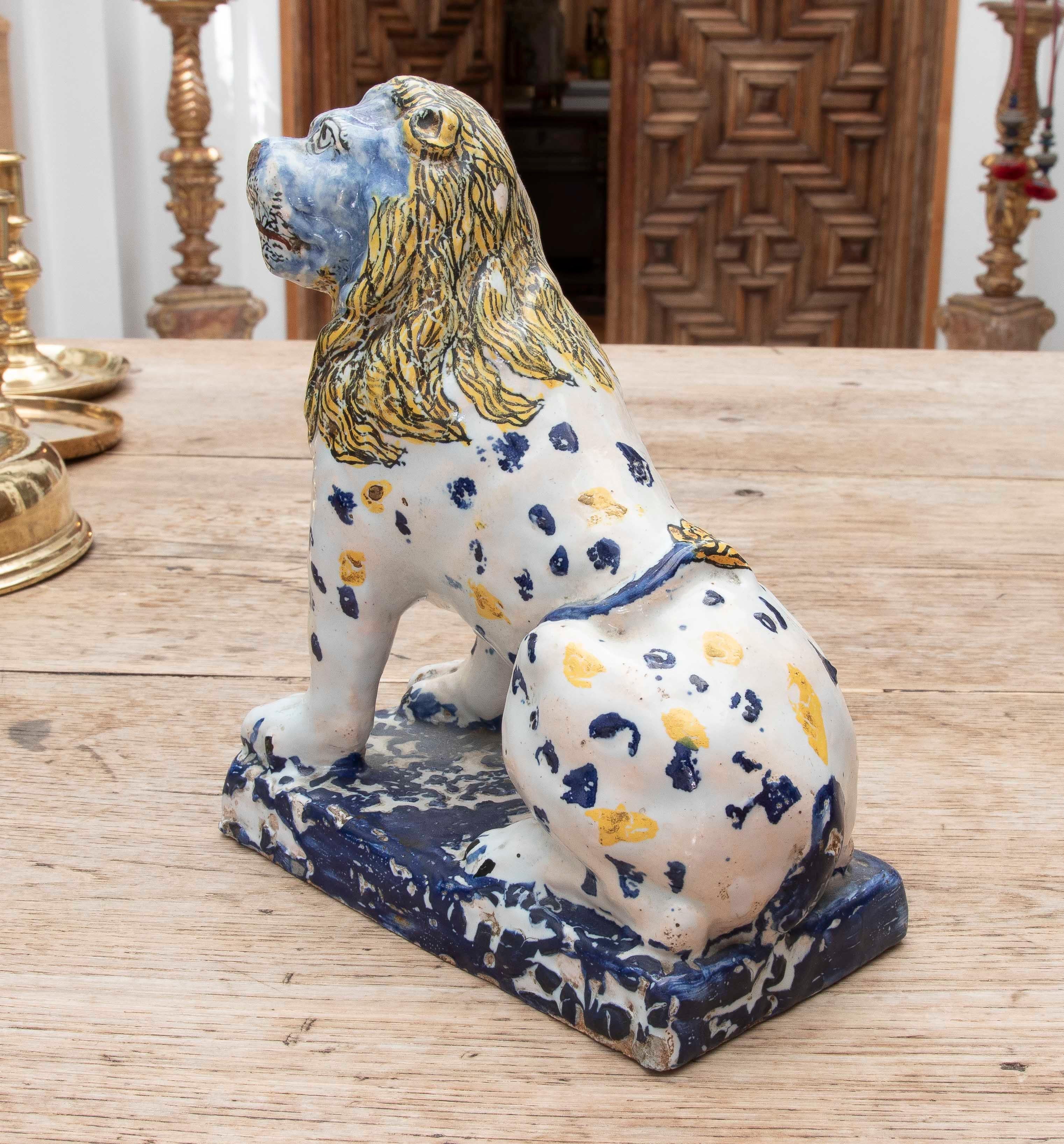 Sculpture of a seated rampant lion, modeled in glazed earthenware and hand-decorated in vivid shades of cobalt blue, mustard yellow, and touches of black, typical of the traditional ceramics of Talavera de la Reina (Spain) or possibly the Puebla