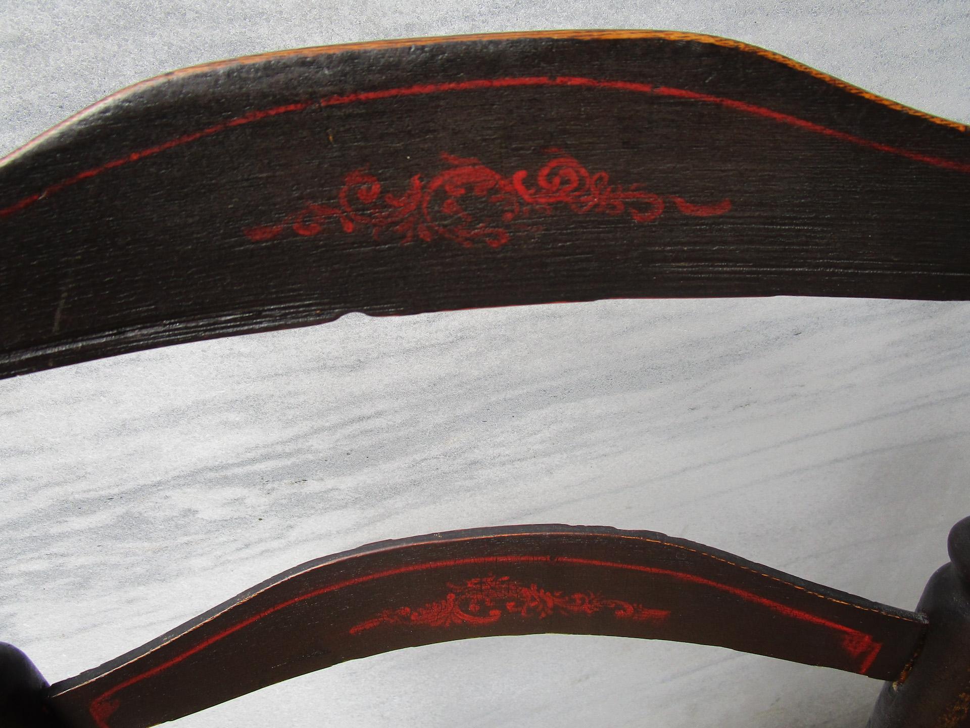 Cette rare chaise à dossier en échelle en chêne peint et décoré au pochoir de la Nouvelle-Angleterre, datant du XVIIIe siècle, présente un châssis inférieur fortement défini, des accoudoirs gracieux se terminant par des boutons ronds, et trois
