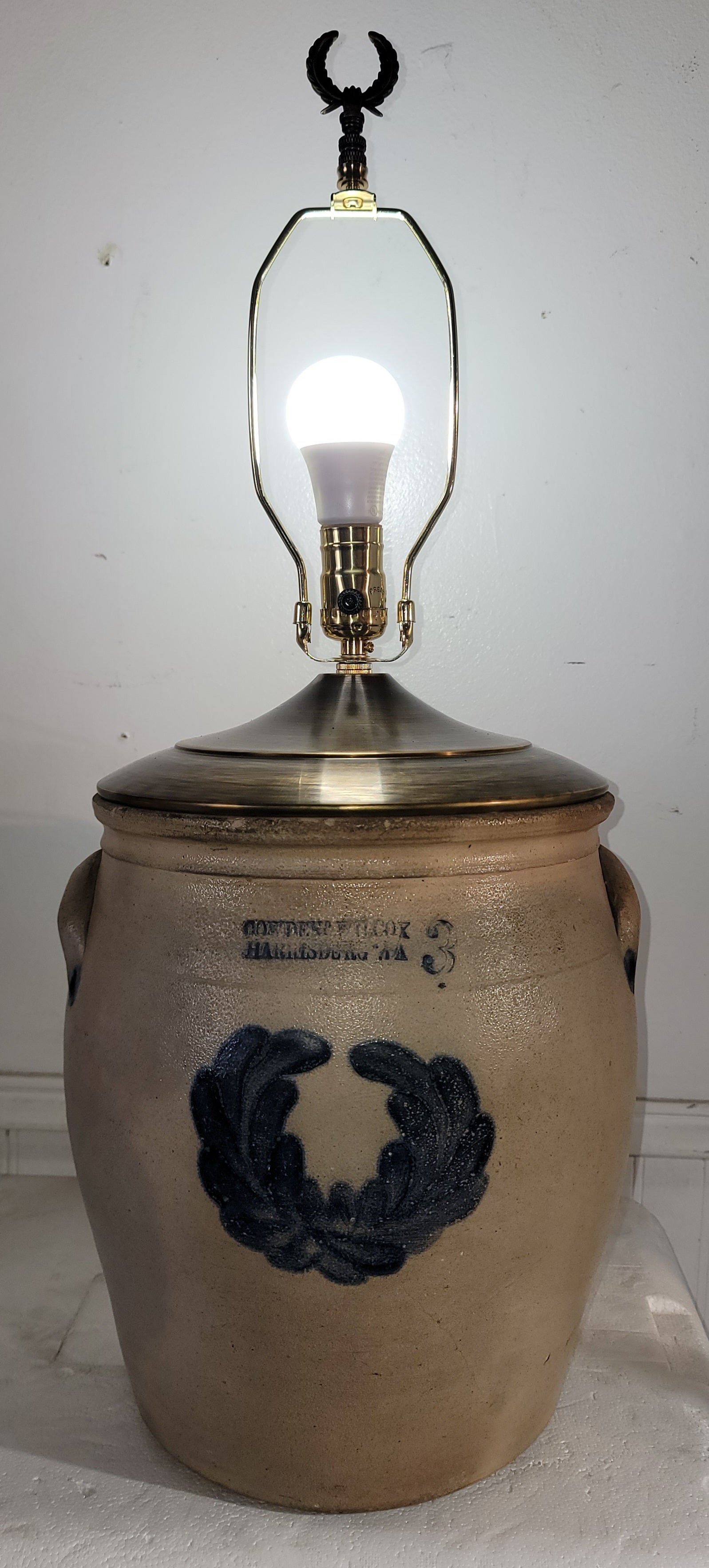 Le vase mesure 11 de diamètre x 28 de haut  L'abat-jour mesure 18 cm de diamètre  x 11 de haut.

Cruche Cowden and Wilcox du 19e siècle à motif de couronnes de fleurs, transformée en lampe de table. Embout en laiton. 
Cette lampe de table