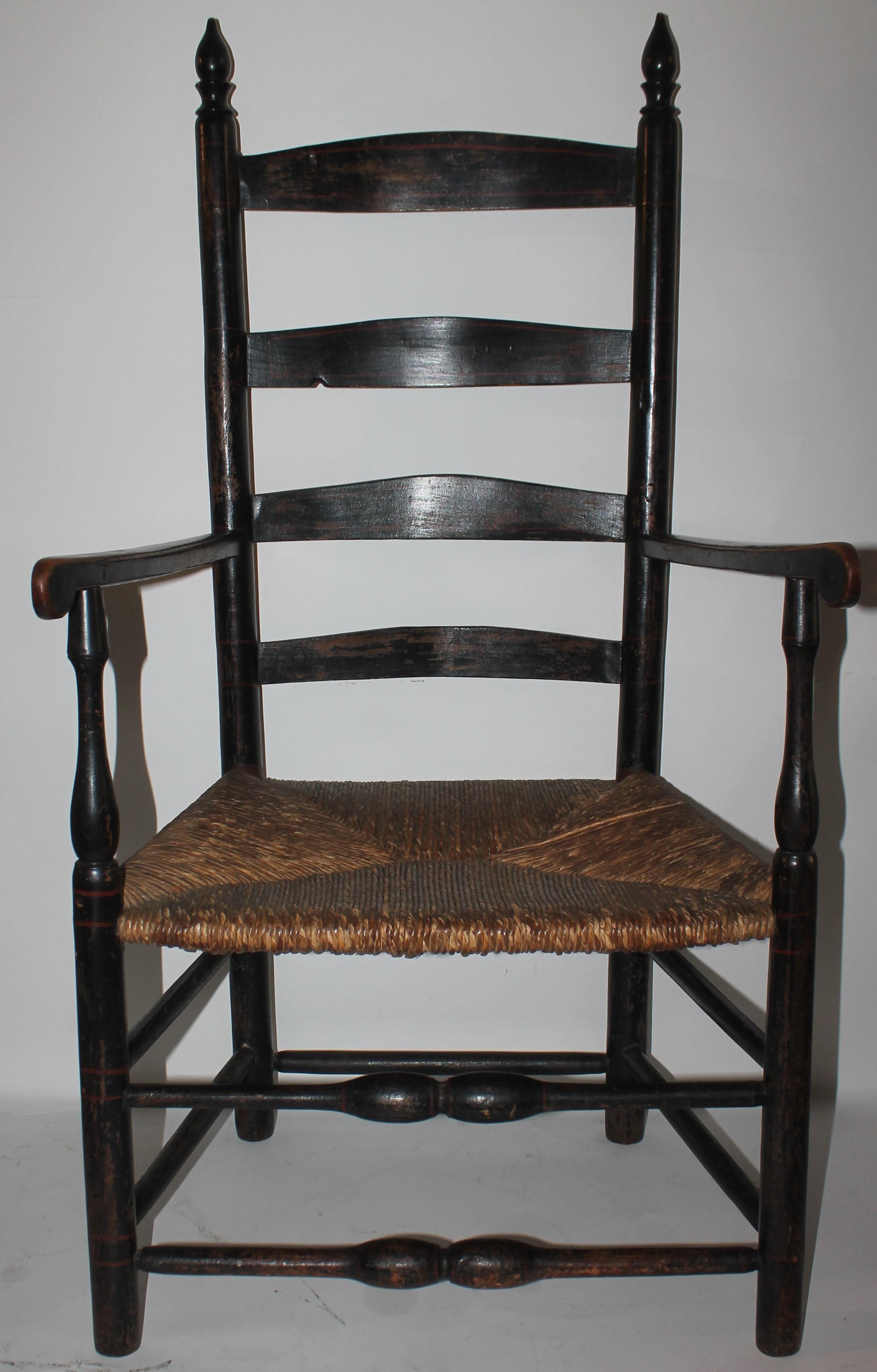 This fine hand made ladder back chair has the original rush seat and original black painted surface. The condition is very good and sturdy with a fine aged patina.