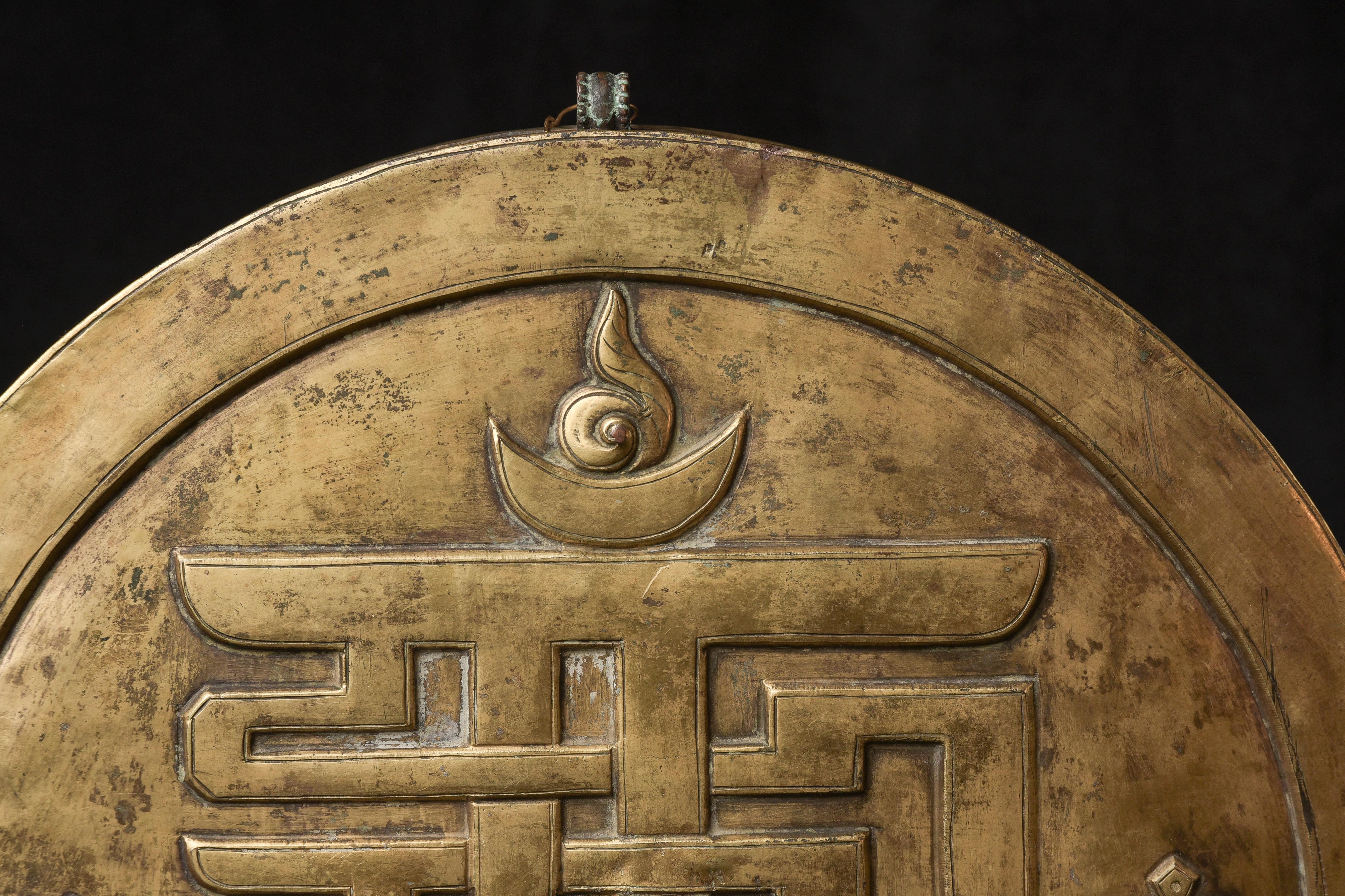 Se trata de un redondel o relicario tibetano del siglo XVIII, de gran calidad, procedente de una antigua finca del noroeste. Parece construido con cobre dorado. Es bastante grande, con casi 25 cm de diámetro. Es hermoso por ambos lados. Su peso es