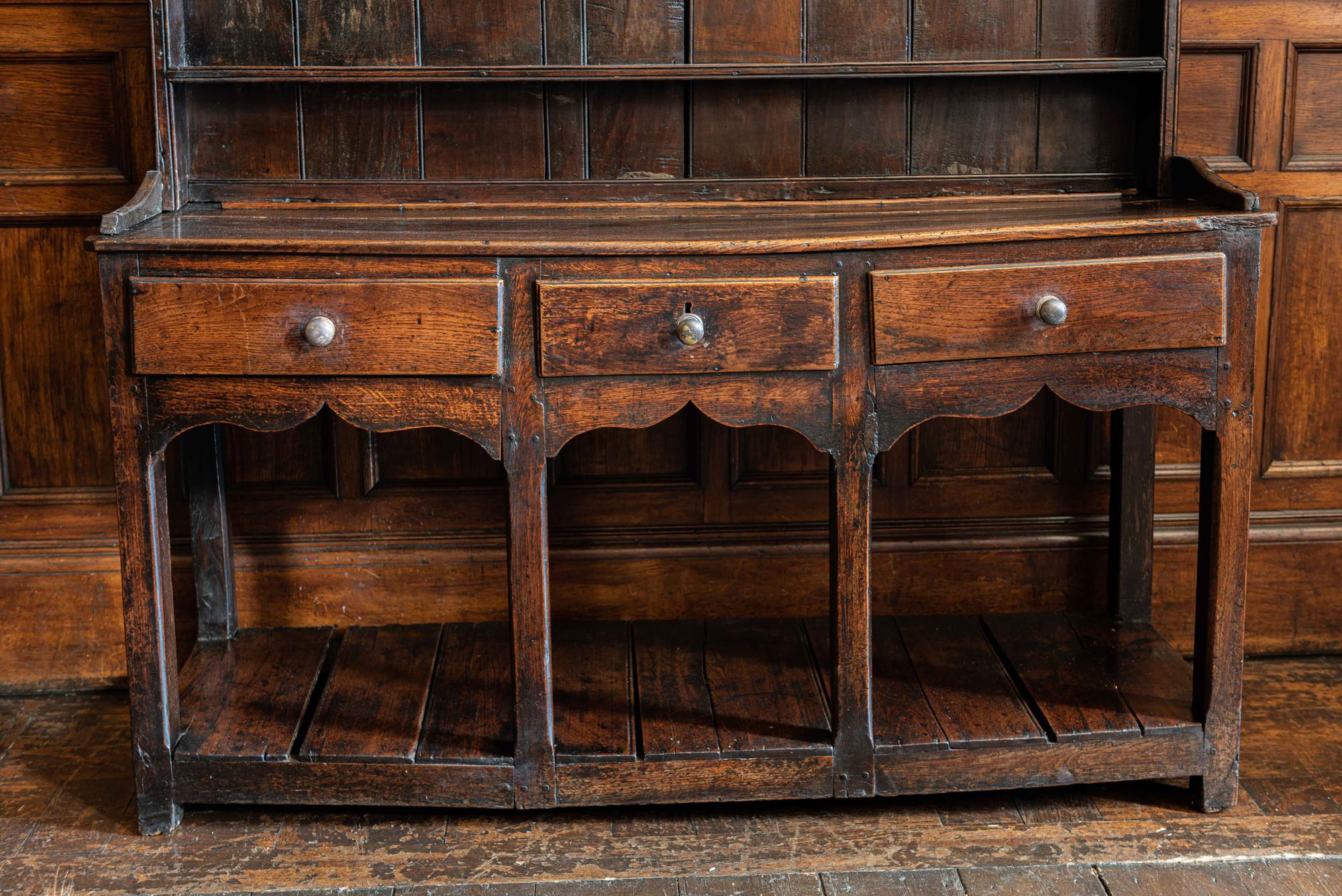 18th century welsh pot board dresser
A diminutive and rustic 18th century welsh mixed oak, ash and pine pot board dresser.
With three central drawers and a country carved apron to the front. Twisty and knarly with great color and patina, an