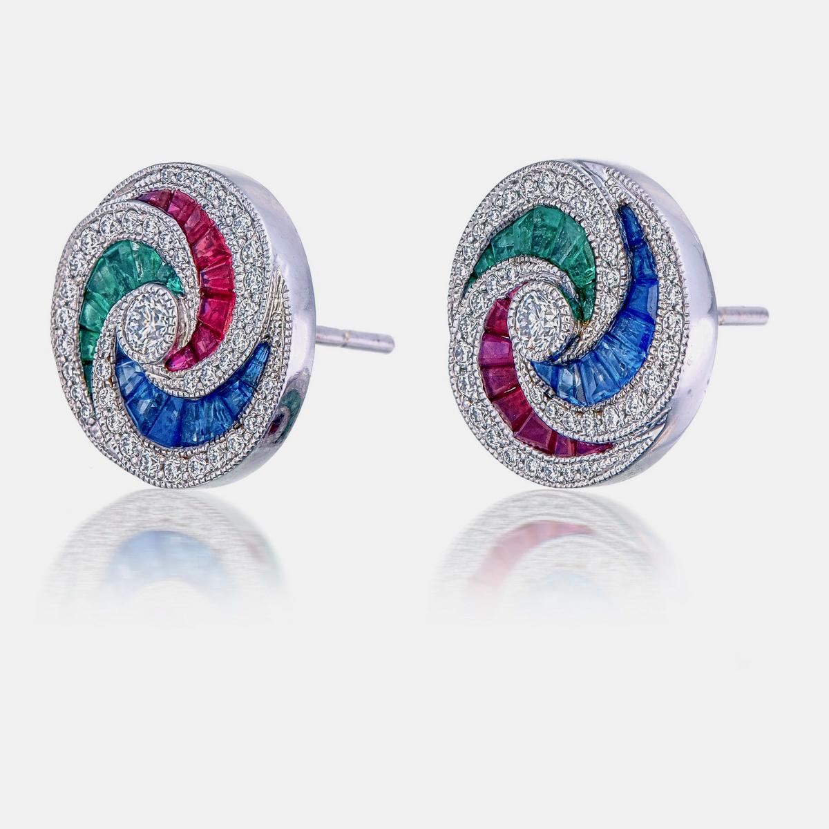 Ces boucles d'oreilles vibrantes présentent une combinaison de 1,9 carats d'émeraude, de saphir bleu et de rubis, créant un design coloré. 

Entourés de 0,66 carats de diamants étincelants, ils apportent une touche d'élégance. 

Confectionnées dans