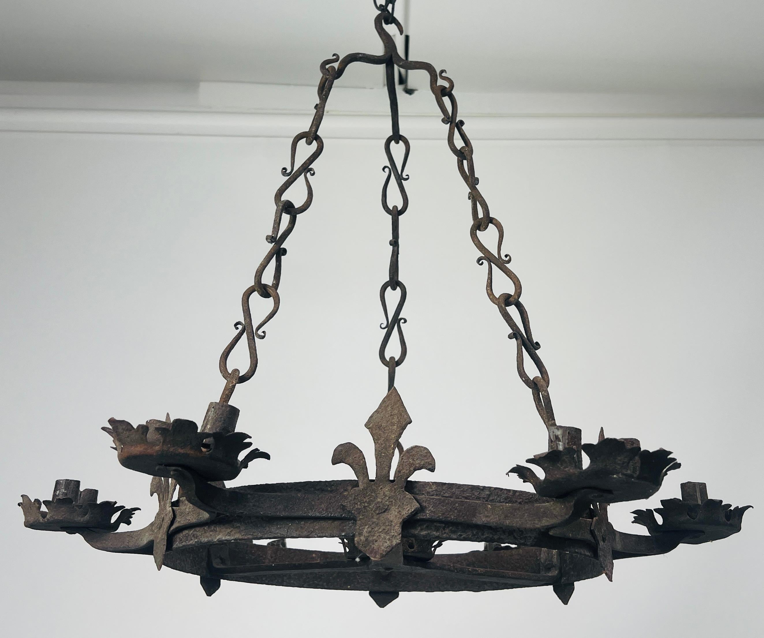 Lustre en fer forgé avec fleur de lys Ce lustre en fer forgé évoque l'élégance du design gothique français grâce à sa fabrication artisanale et à sa silhouette intemporelle. Le cadre circulaire supporte 14 lampes de style bougie.  Les bobesch