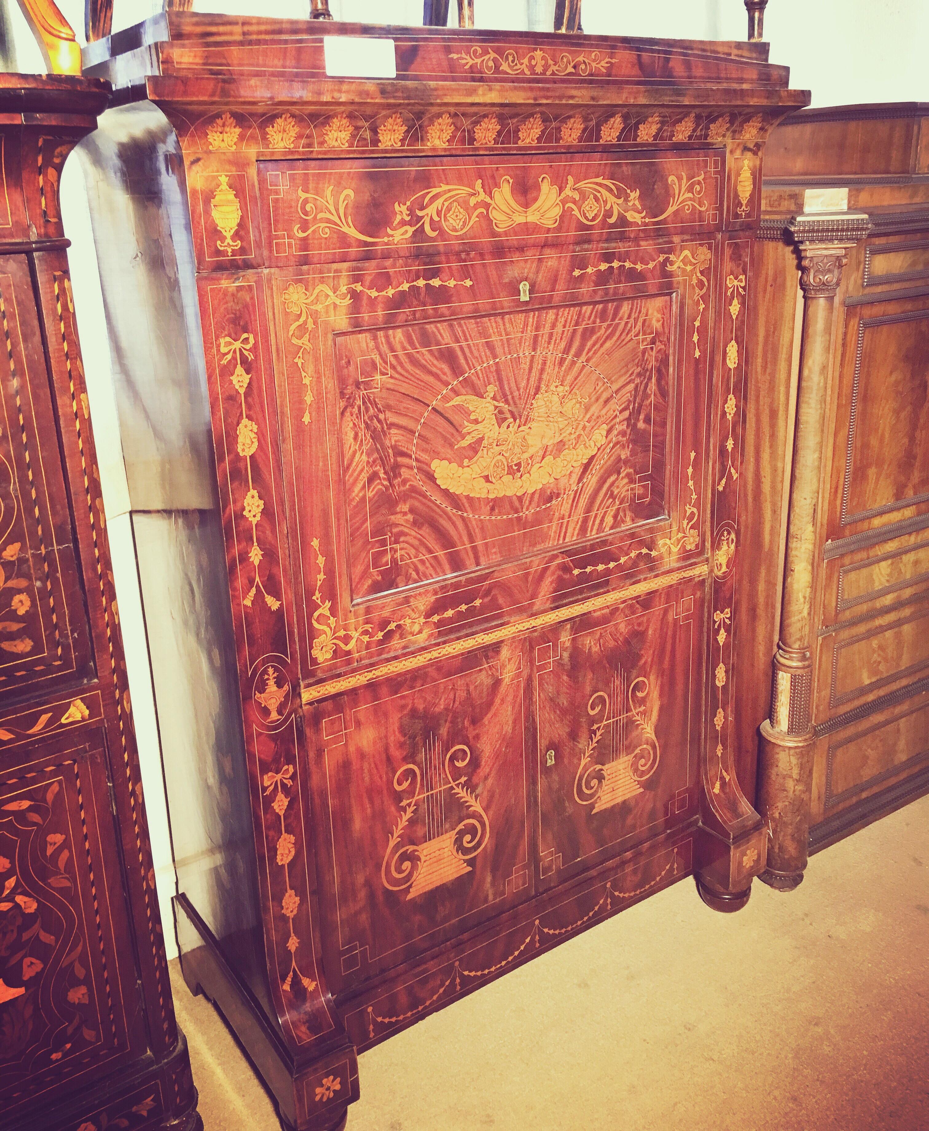 Fantastic Dutch secretaire in mahogany veneer. Rich decoration of inlays with motifs of urns, flower loops and horse carpets. Front with fold-down writing disc, two drawers and door pairs.
On the front with an inlay depicting Apollo on the chariot