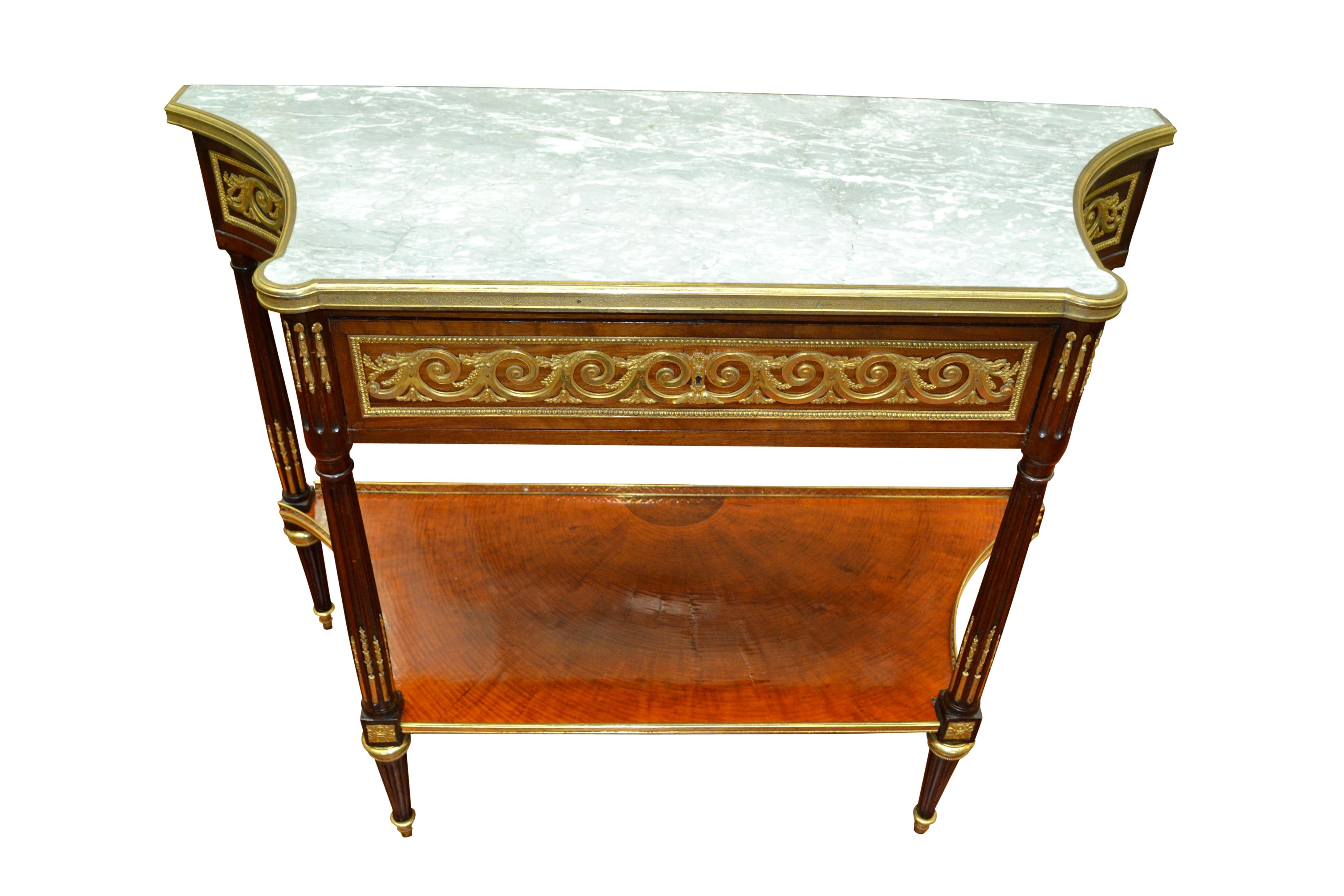Der Desserttisch im Louis XVI-Stil ist aus Mahagoni gefertigt, dessen Oberteil reich mit vergoldeten vitruvianischen Bronzeschnecken und anderen dekorativen Beschlägen verziert ist, die alle von Dasson oder Linke stammen. Der obere Mittelteil
