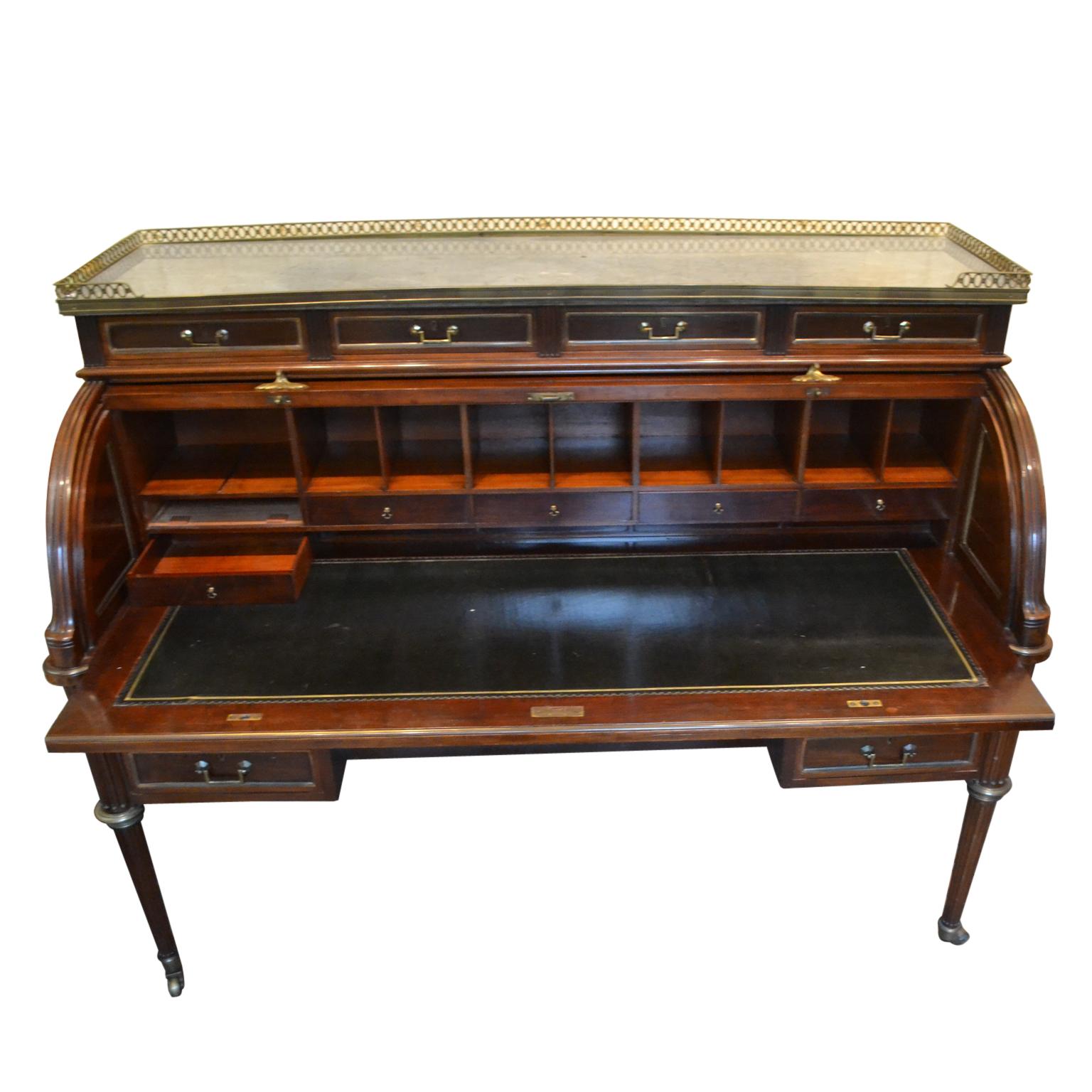 A palatial scale mahogany cylinder desk in the Louis XVI style; the superstructure with rectangular galleried bleu turquin marble top over four frieze drawers, the paneled cylinder front opening to reveal a fitted interior with leather lined writing