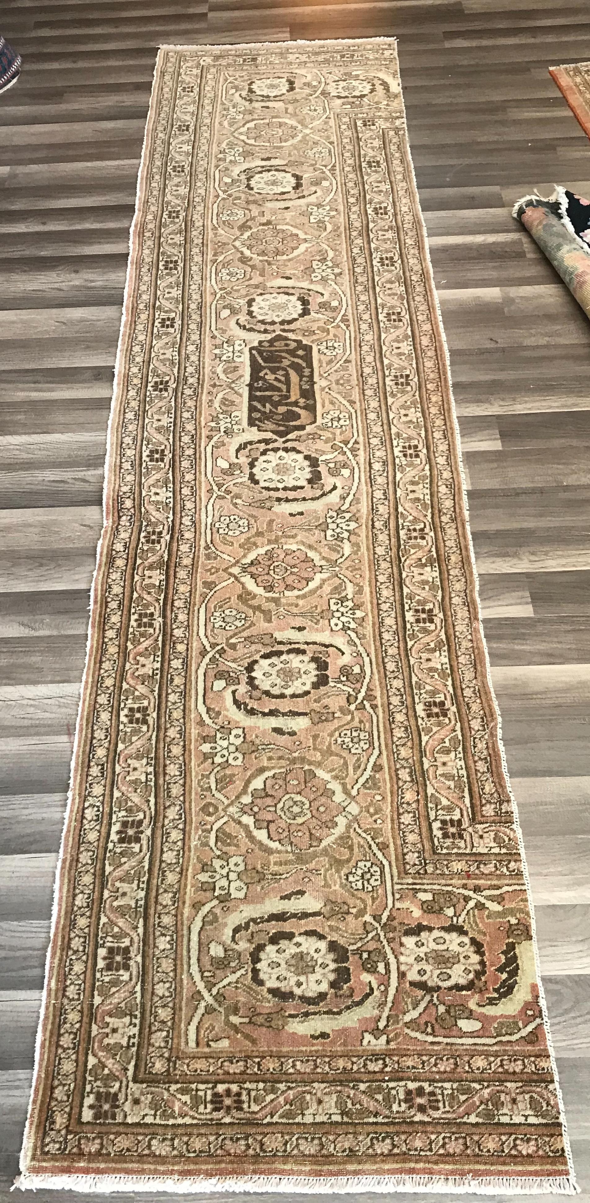 Beautiful antique hand woven Persian rug fragment with the signature of the rug maker family on it, very muted soft colors of flowers and vines motifs all around. This piece of woven art was part of a very large rug that during time got damage in