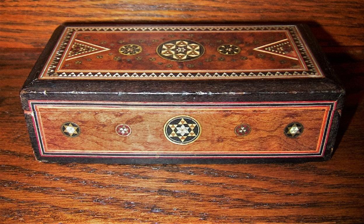 Gorgeous little Indo-Persian Mosaic Trinket Box from circa 1870.

19th century Indo Persian Mosaic Trinket Box with Amboyna.

Mosaic inlay with gold, semi precious stone, pewter, etc.

The box has a very Persian feel and influence to it. The