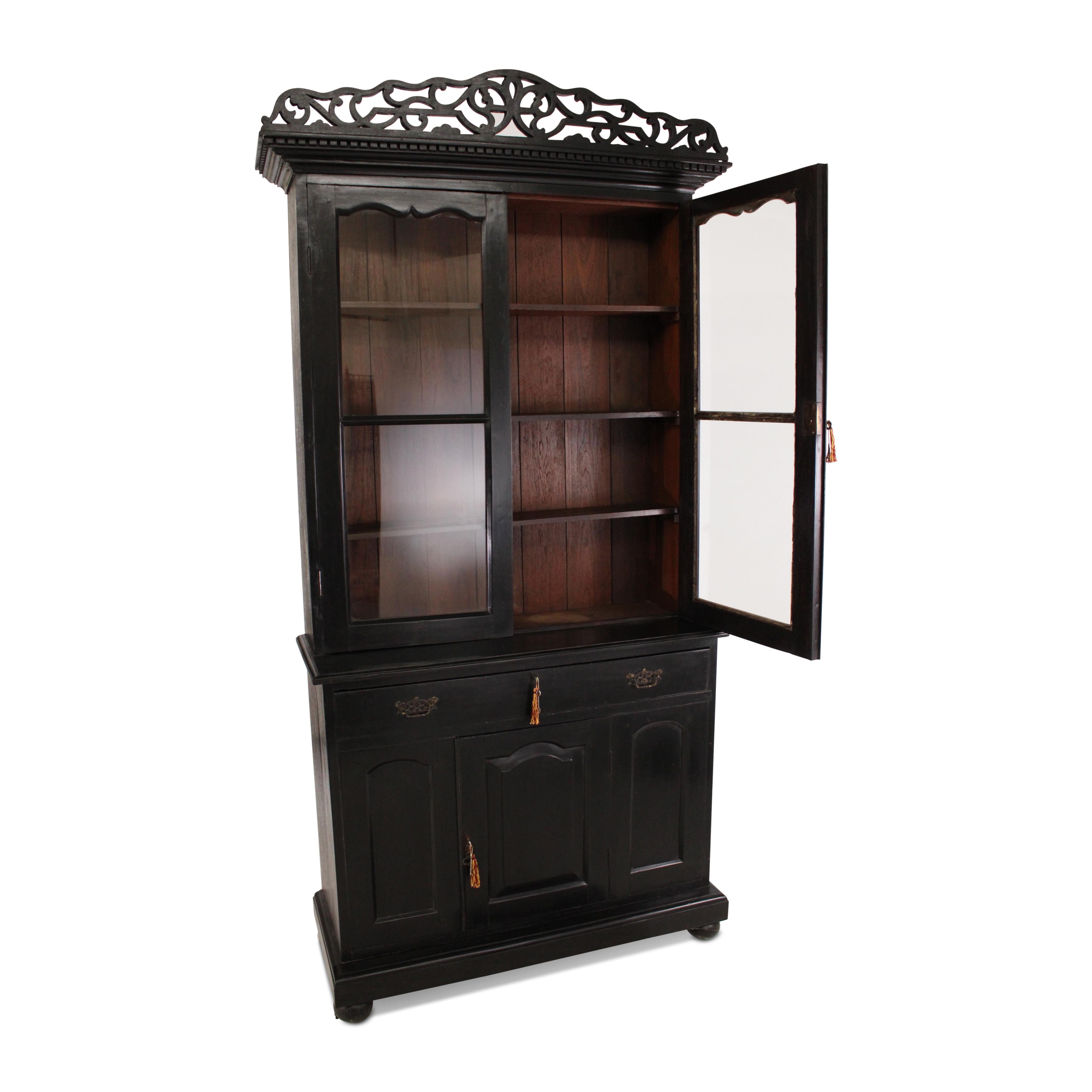 A lovely Anglo-Indian teak cabinet or bookcase. Retaining its original polish, it displays a beautiful patina and features a pair of glazed panel doors at the top, a central drawer, and a paneled door at the bottom. This cabinet is elegantly
