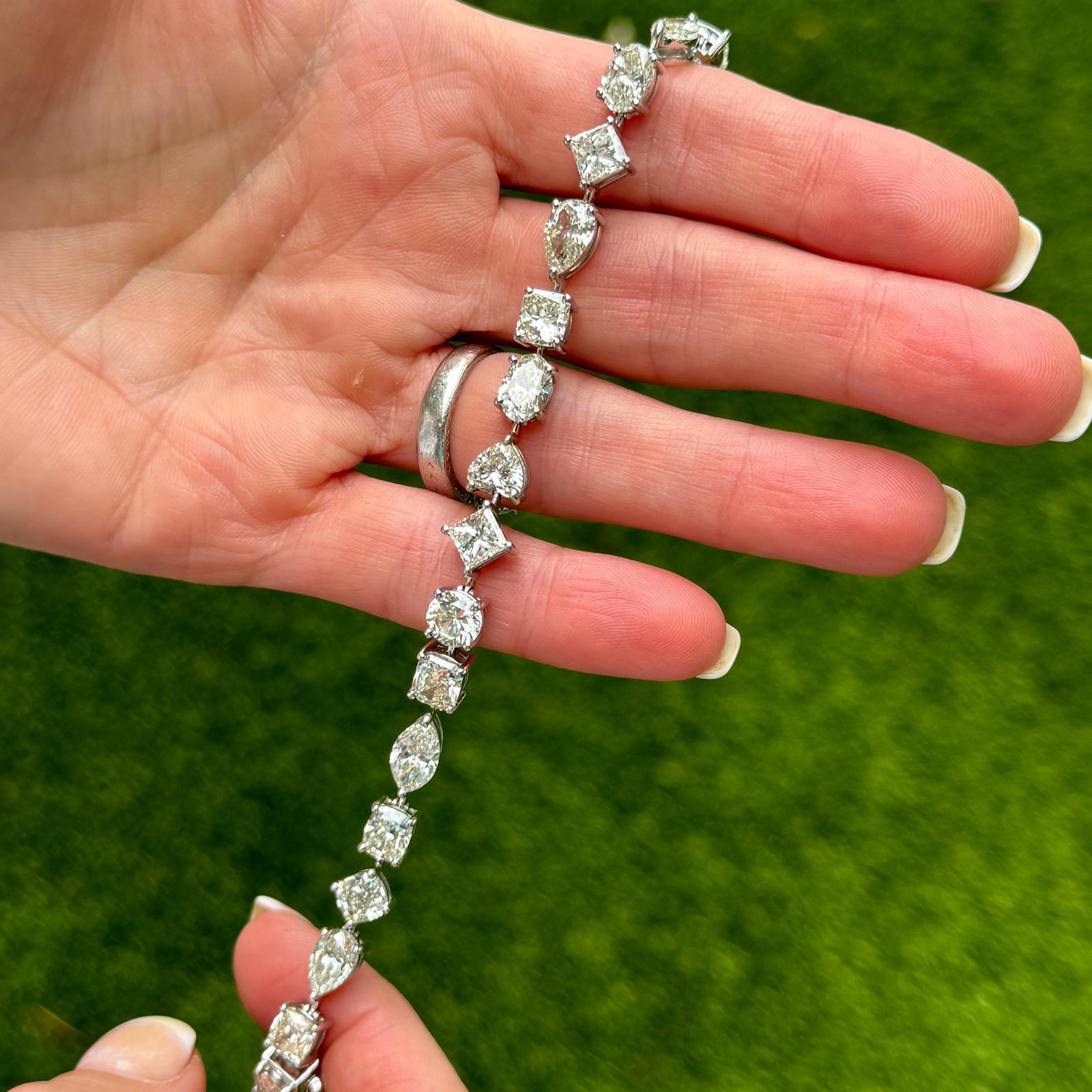 Ce superbe bracelet en ligne de diamants de taille mixte présente un éventail de diamants de taille cœur, ronde, ovale, marquise, princesse, rayonnante et coussin, chacun pesant au moins 1 carat. Serti dans un luxueux or blanc 18 carats, le bracelet