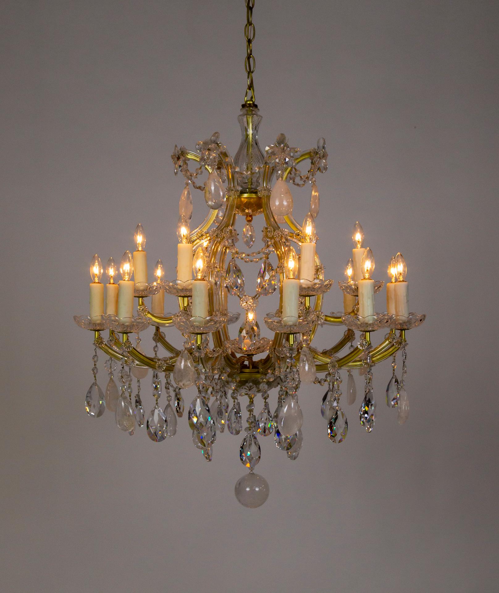 A large, Maria Theresa style chandelier from the later 20th century decked with large rock crystals and highly prismatic, cut, leaded crystals. It has 18 arms in two tiers and one center light that illuminate the crystals beautifully. It has