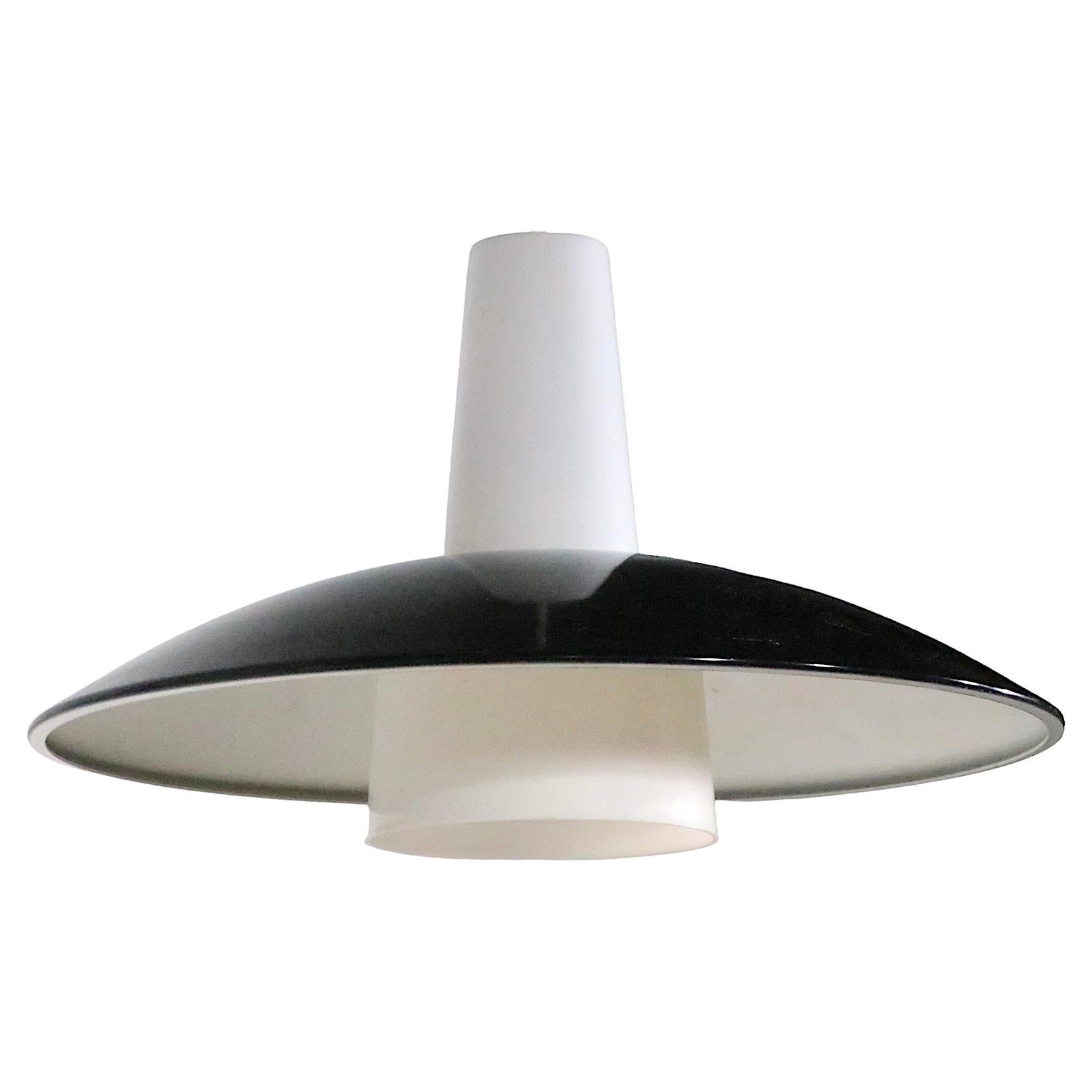 Chic architectural pendant chandelier(s) originally from the landmark SUNY Albany campus, which was designed in 1962 by Edward Durell Stone. The fixture features a domed disk shade, having a black top with a white interior bottom. The  metal shade